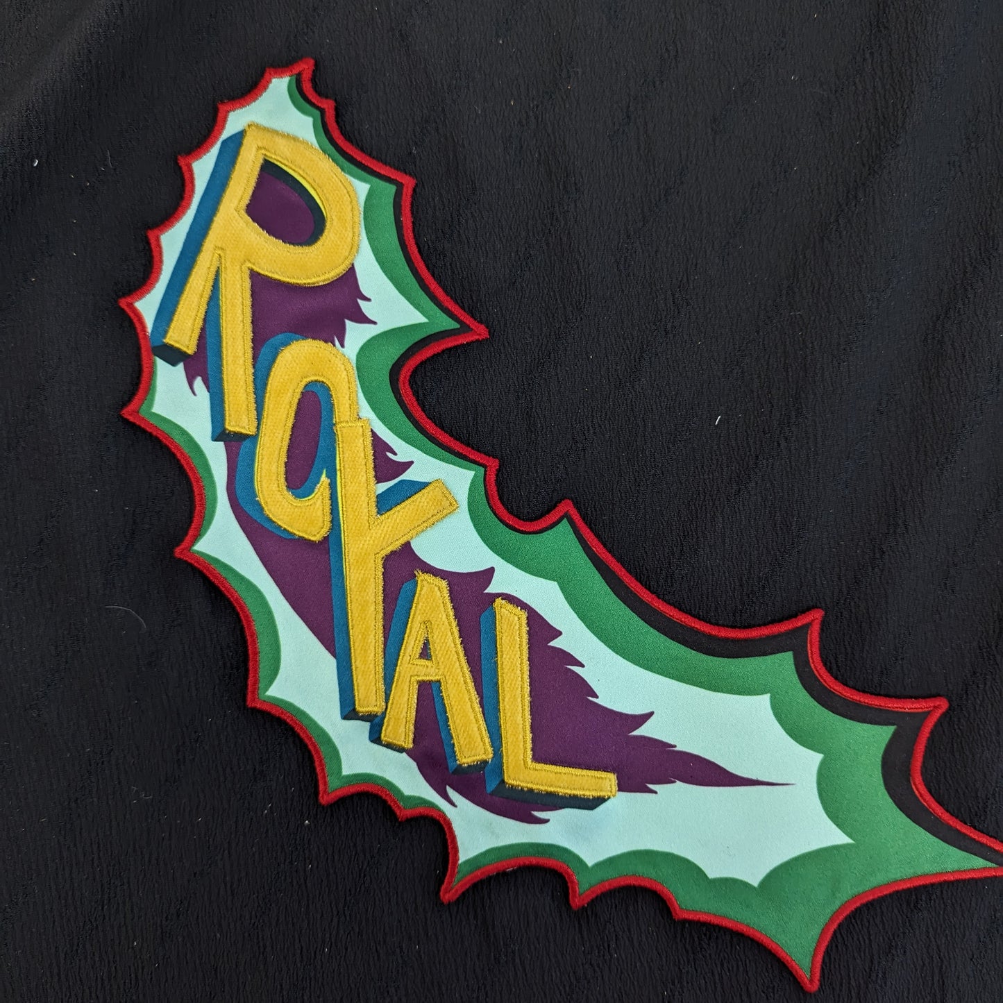 Embroidered "ROYAL" patch, 33x11cm, with yellow letters, purple, blue, green, and red accents on black.