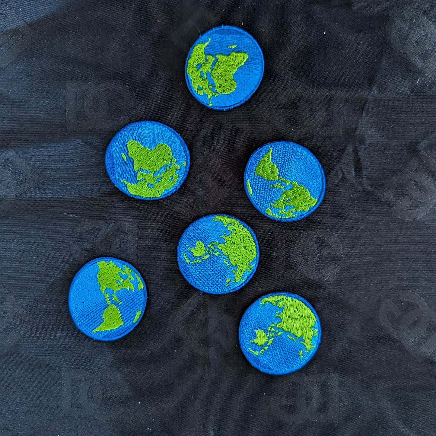 Six round blue and green embroidered Earth patches, 3.5 cm, on a dark fabric background.
