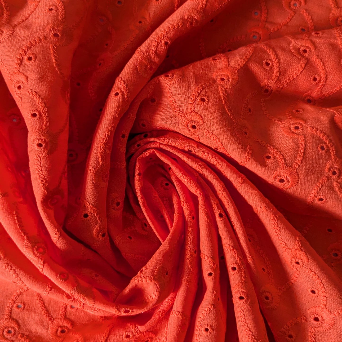 Flame red Sangallo deadstock lace fabric with intricate eyelet embroidery and a scalloped edge.