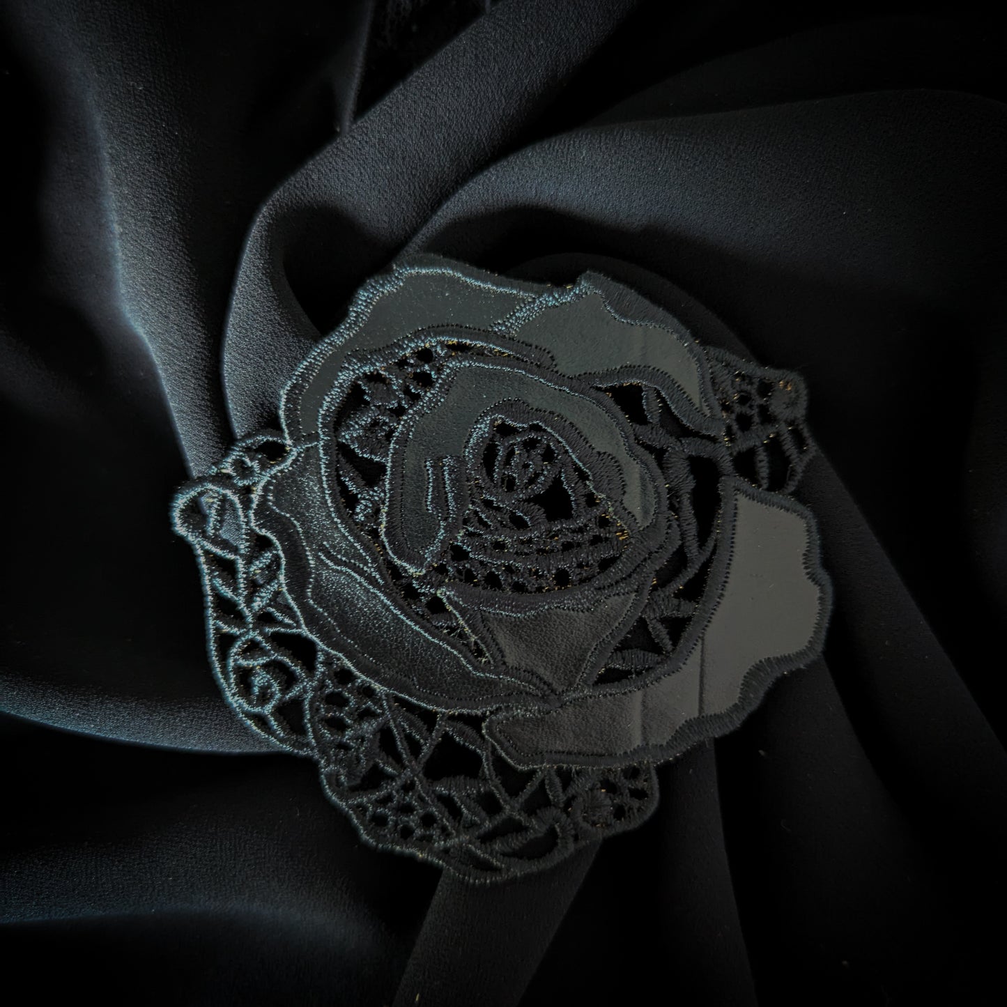 Black D&G rose patch with intricate lace and leather details, 8x9 cm, on dark fabric.