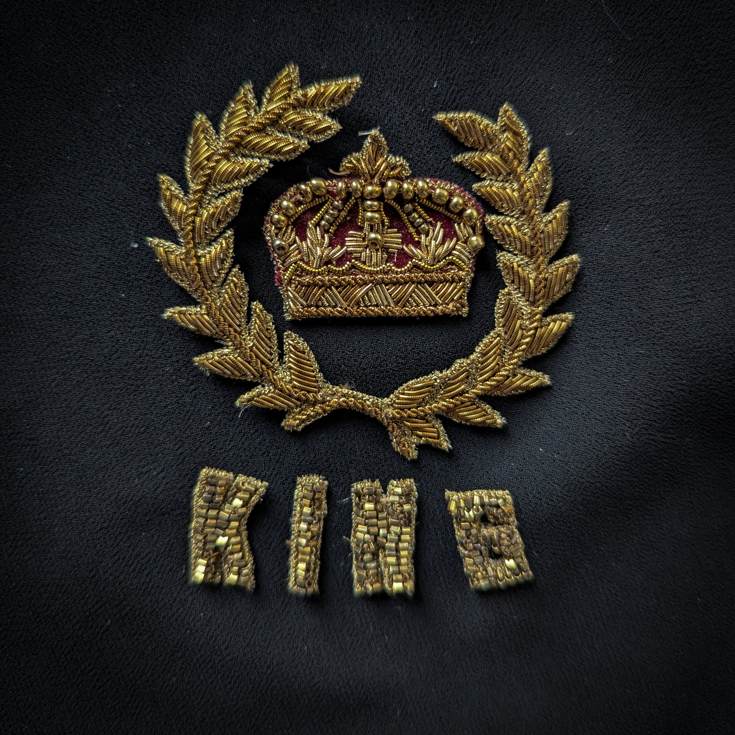 Embroidered gold D&G patch with a crown and "KING" text on a black fabric background, 7x7 cm.