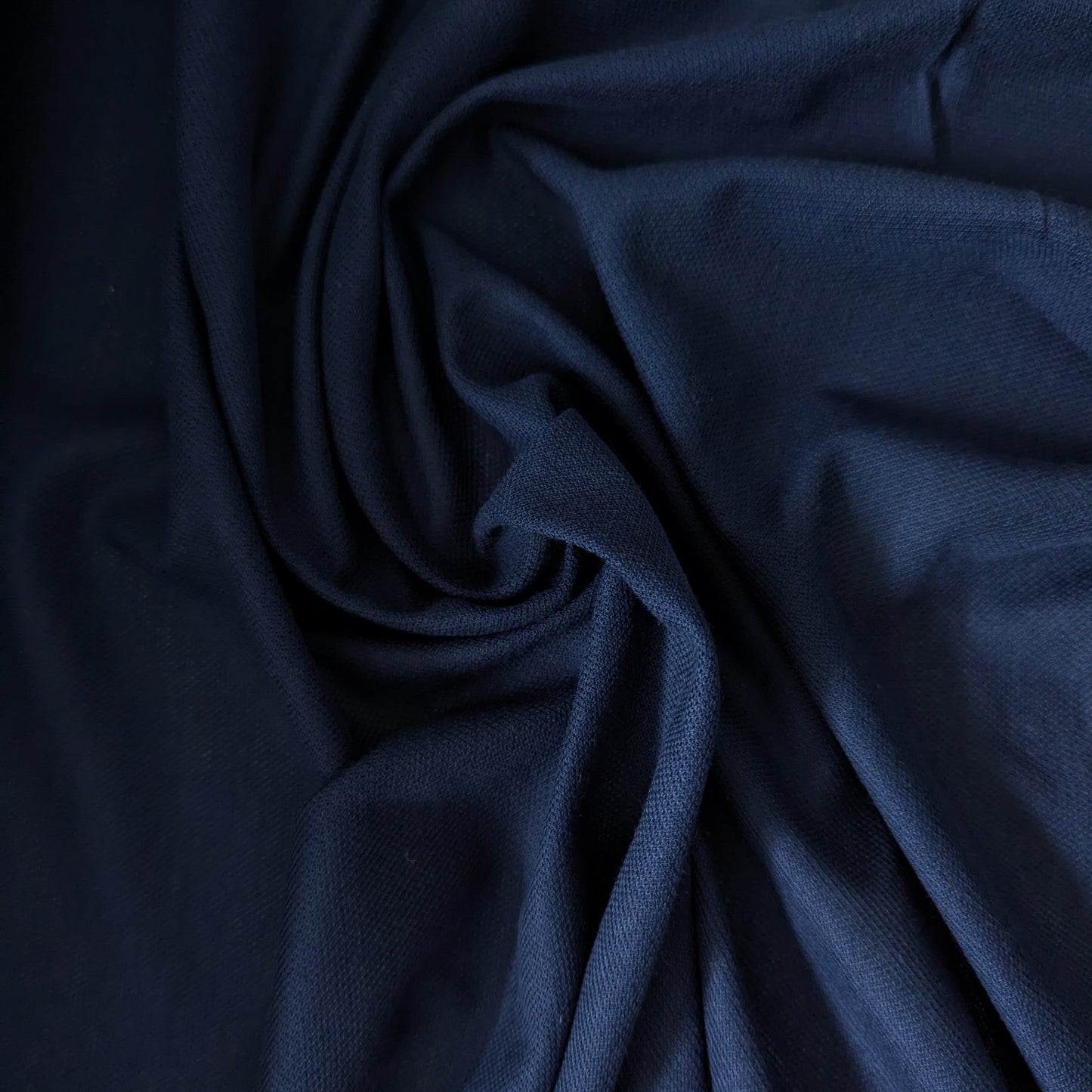 Navy blue cotton cashmere pique deadstock fabric, 150cm wide, with a subtle textured weave and soft folds.