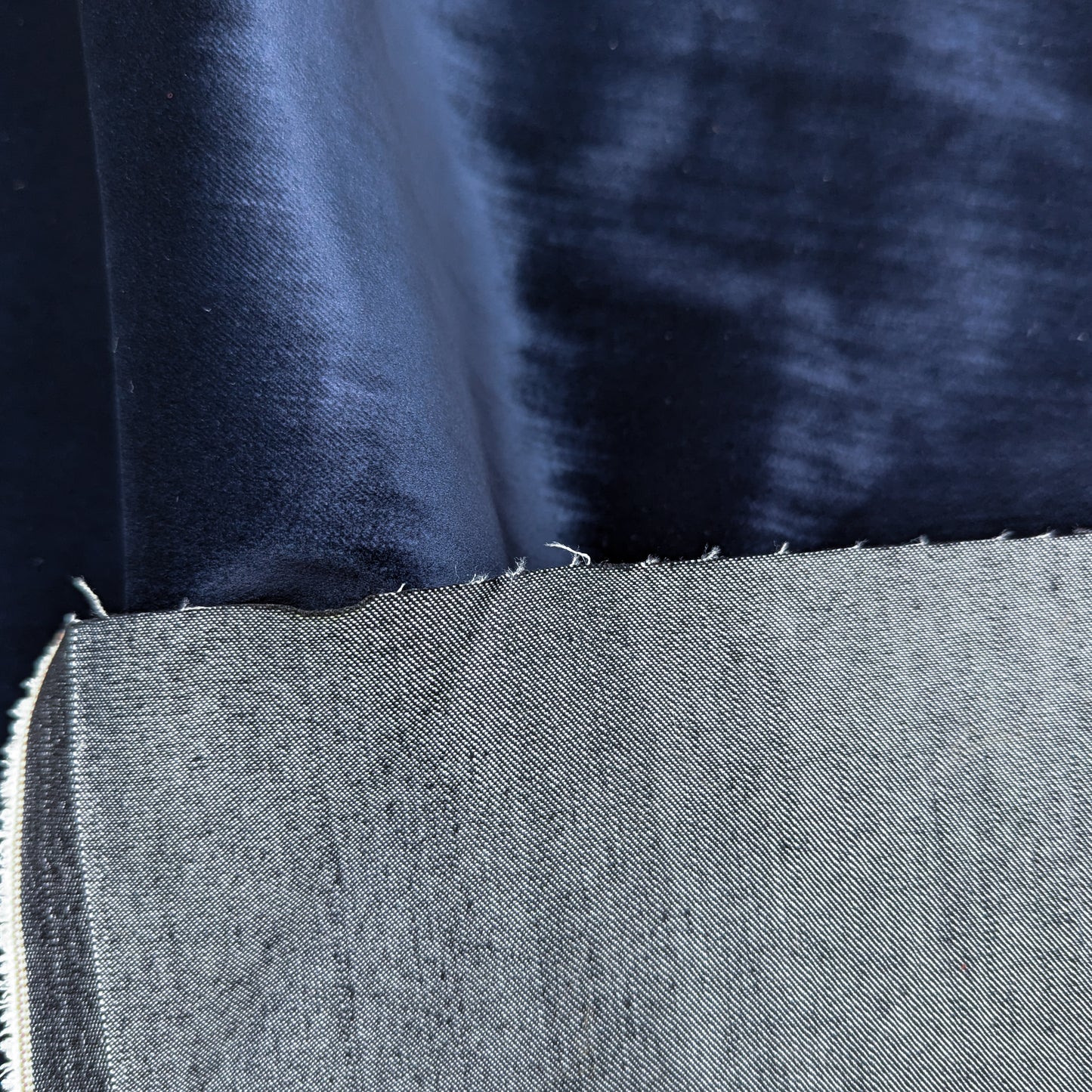 Dark blue velvet denim fabric, showing its soft, plush surface and raw selvedge edge.