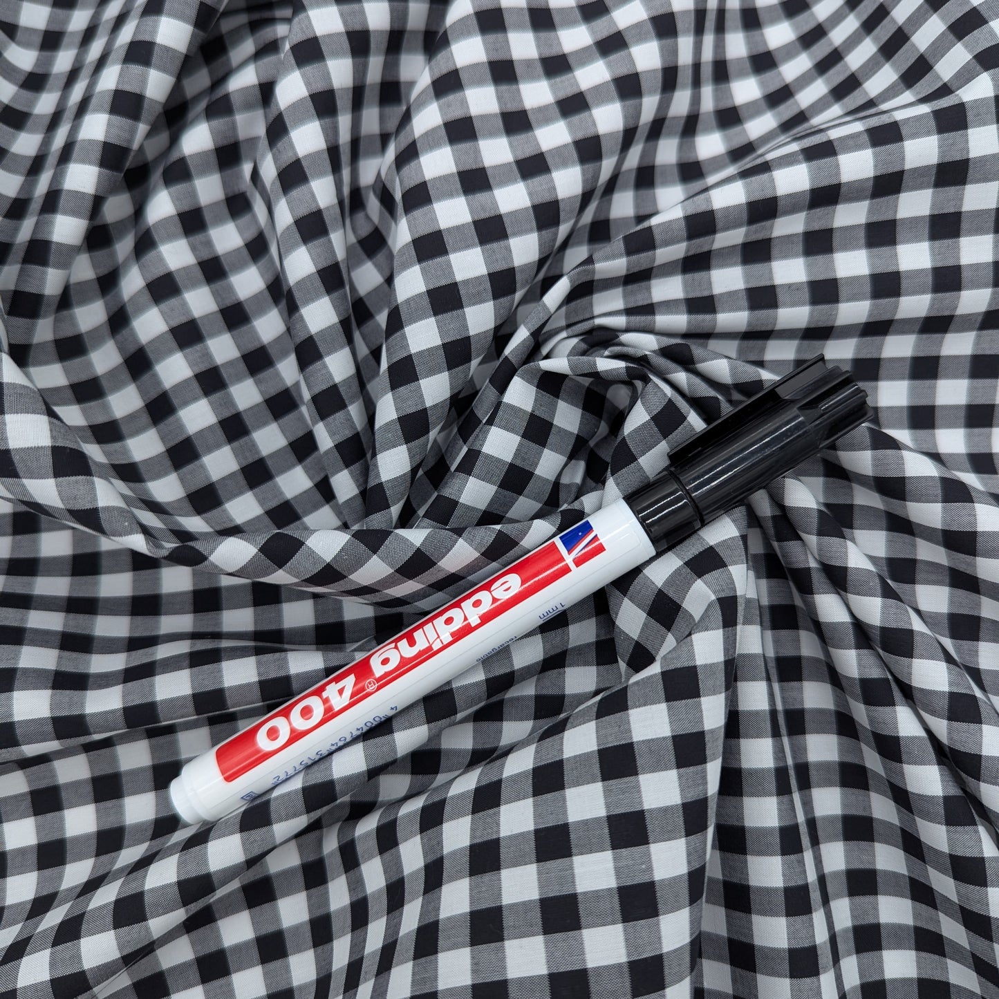 Draped black and white Vichy cotton poplin fabric, 145cm wide, ideal for creative sewing projects.