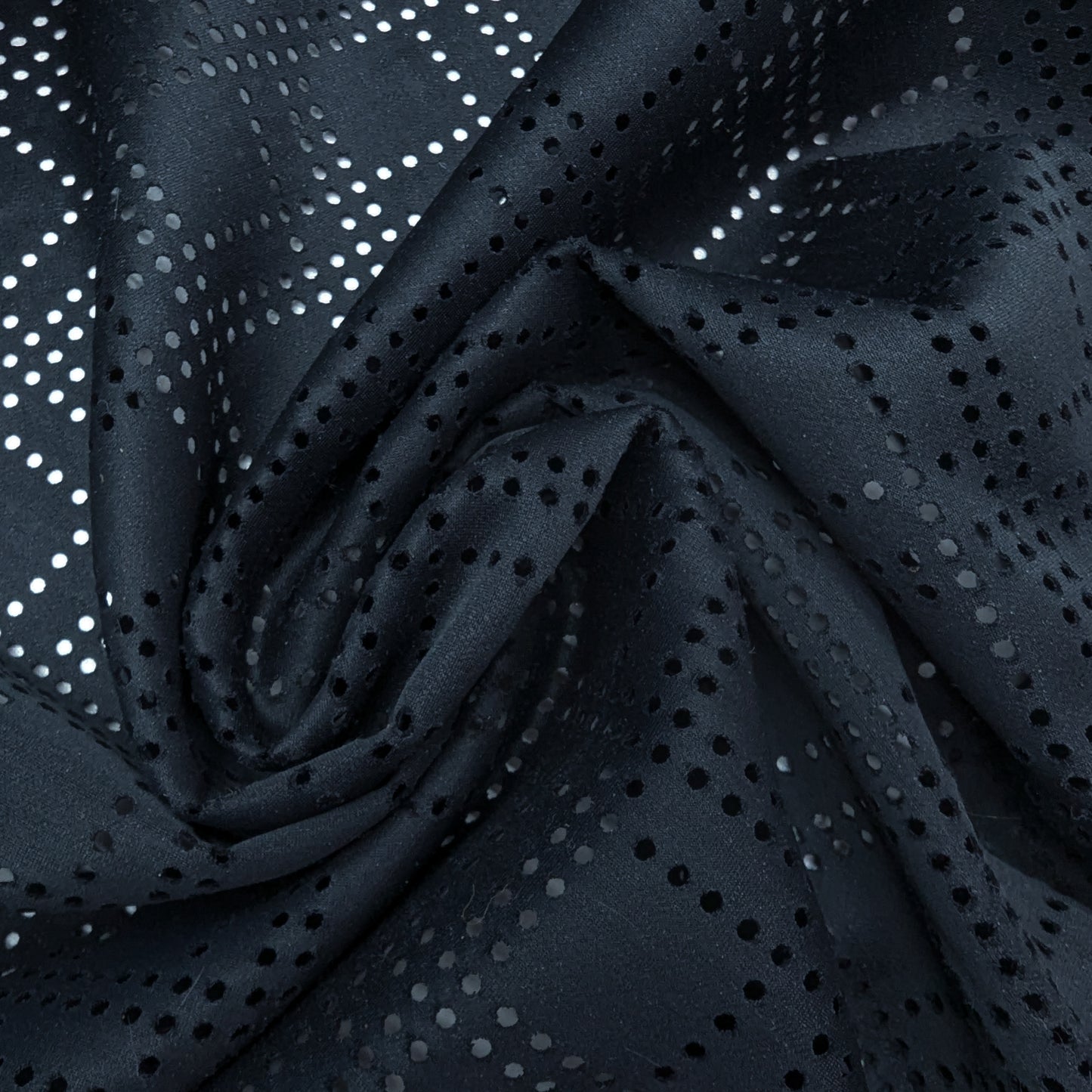 Black Beauty Woll-Viskose deadstock fabric with intricate laser-cut perforations, draped in soft folds.