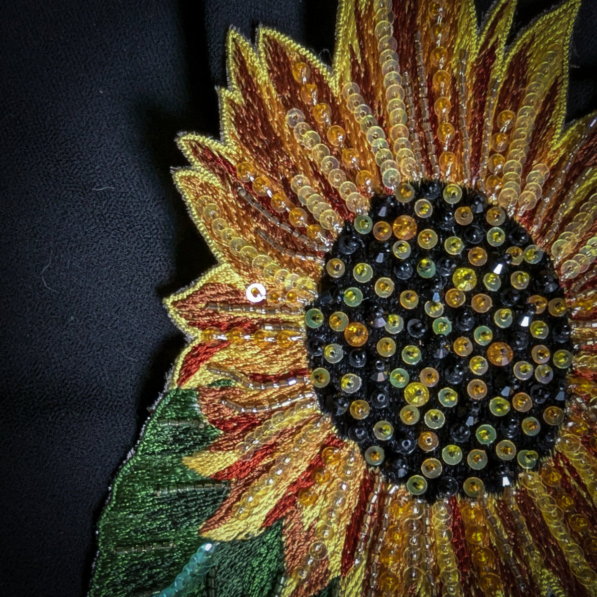 Embroidered sunflower patch with yellow, orange, and brown petals, black center, and beaded accents.