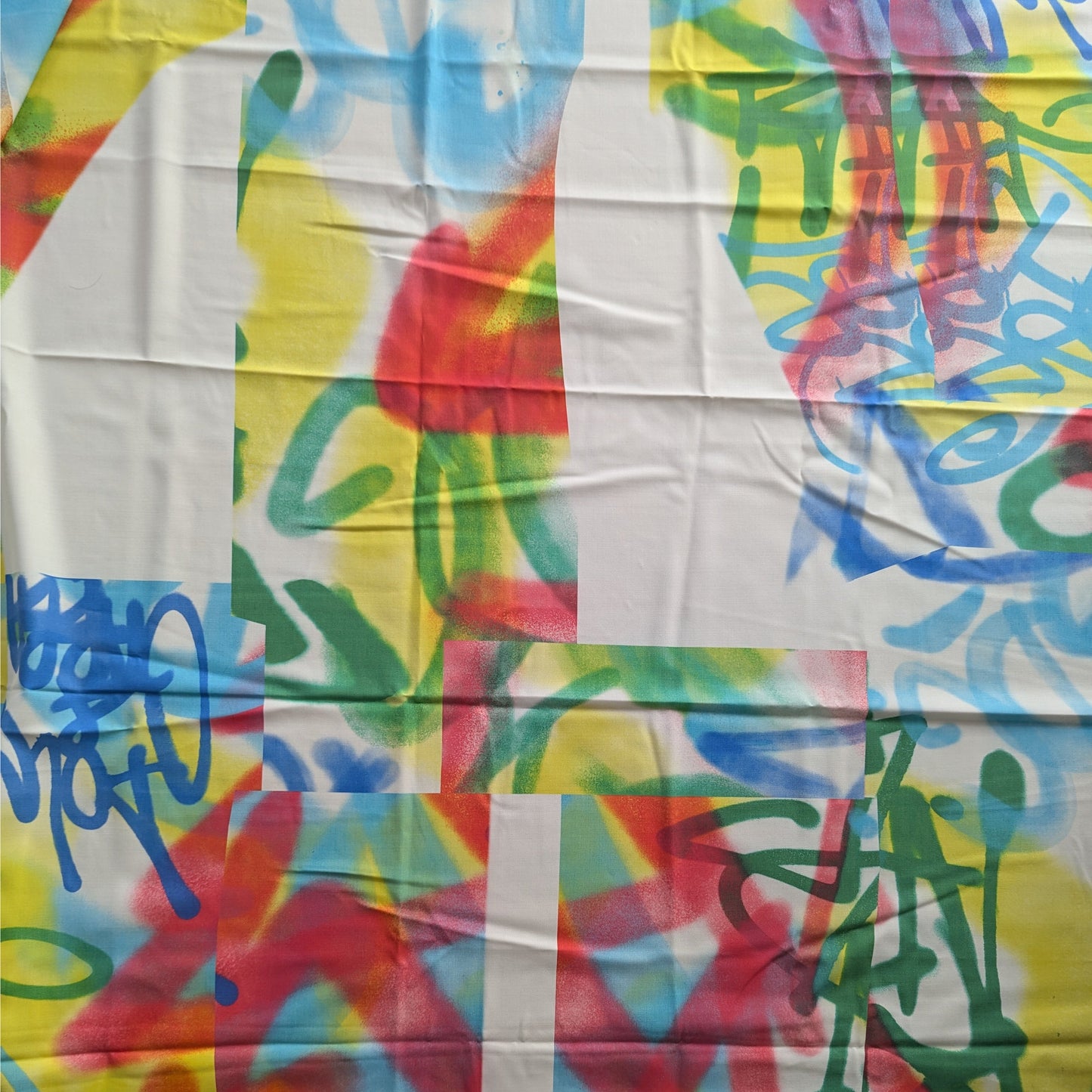 D&G deadstock wool twill fabric with colorful graffiti print in red, blue, green, and yellow on white.