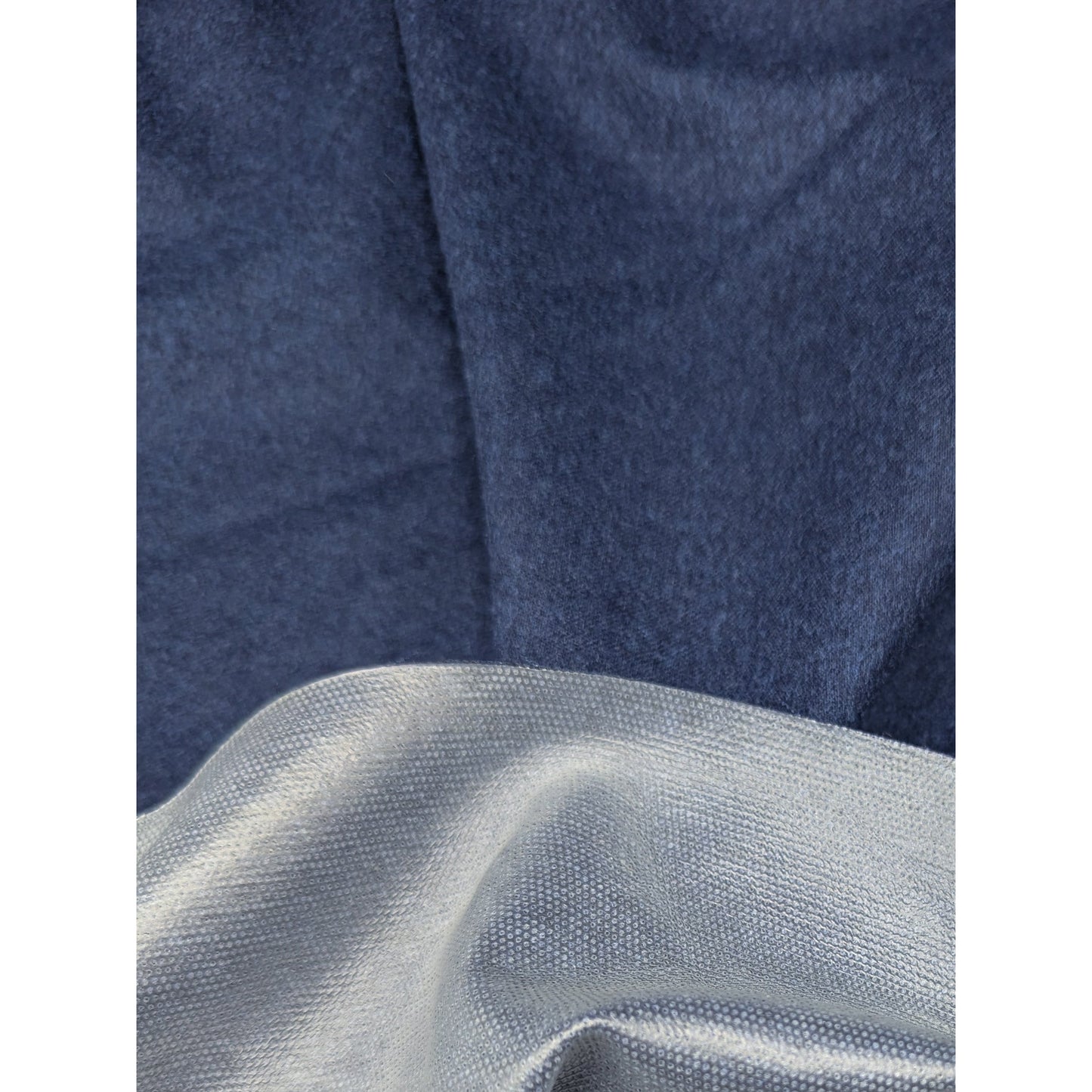 Dark blue wool fabric with a subtle texture, draped over a lighter, textured fabric.