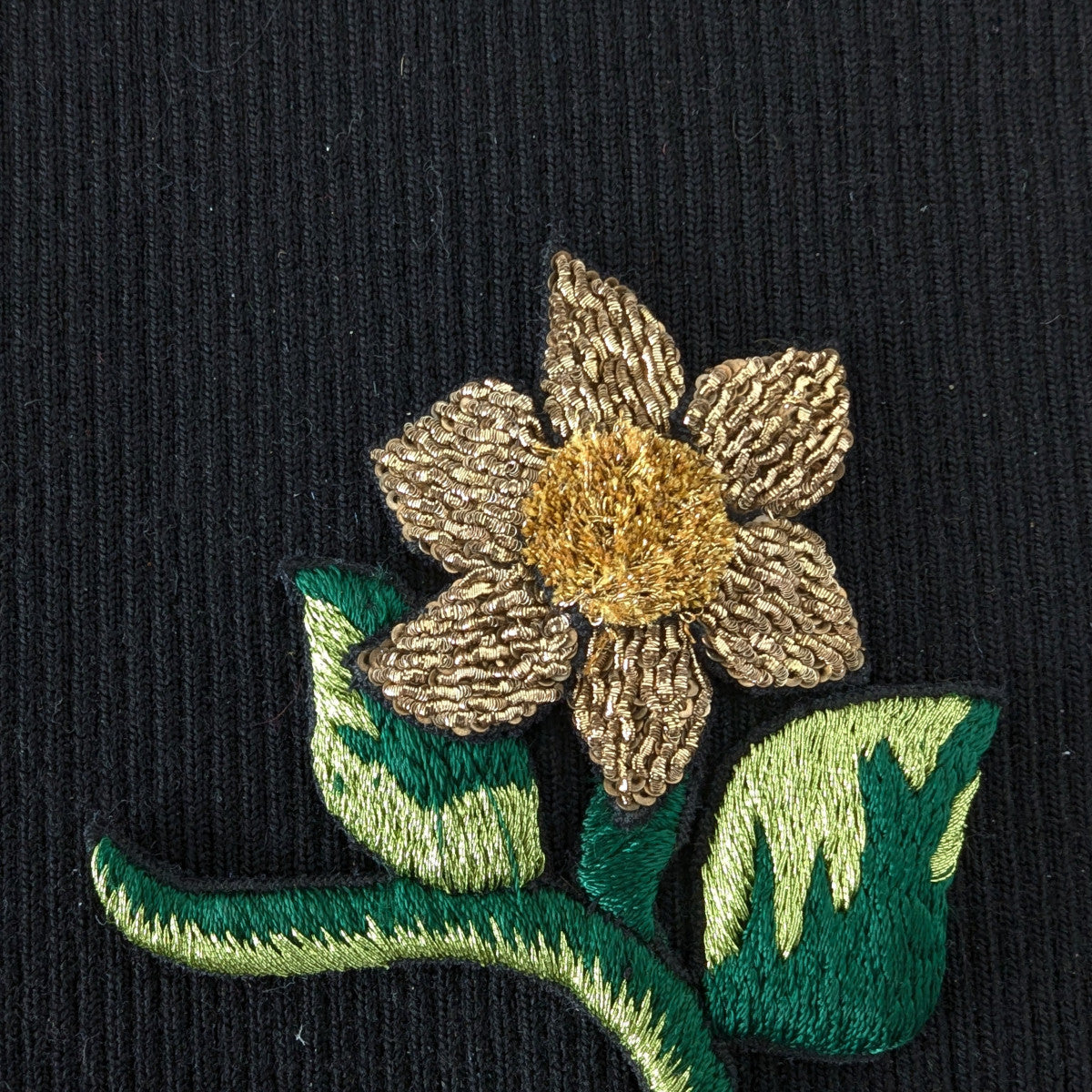 D&G gold and green embroidered flower patch, 13cm, on black fabric.