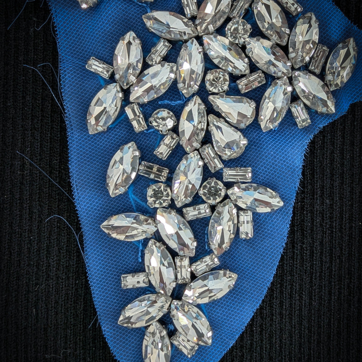 D&G blue patch with sparkling clear Swarovski stones in various shapes, on black fabric.