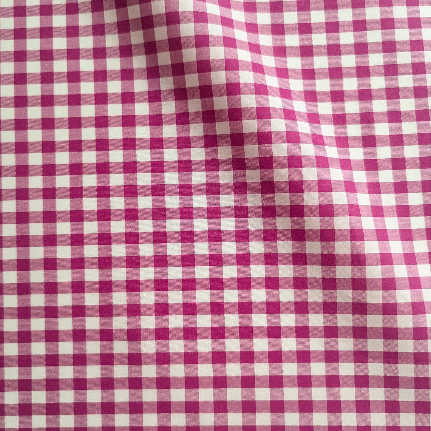 Magenta and white gingham cotton poplin fabric, 145 cm wide, with subtle folds.