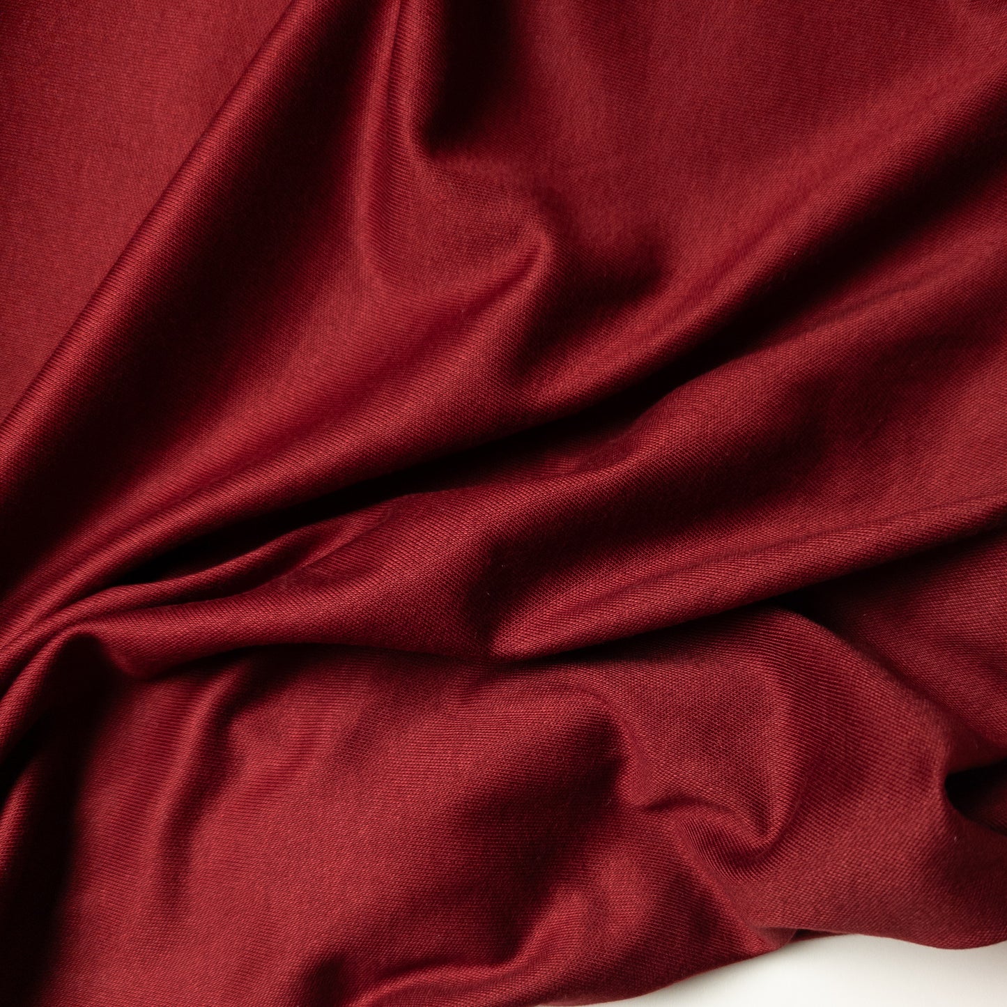 Deadstock E*ro jersey fabric in Pantone Wine Red, 140 cm wide, with soft drapes and subtle texture.