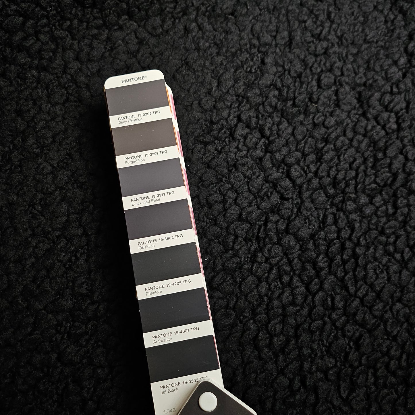 Textured black heavy wool bouclé fabric with a Pantone color swatch showing Jet Black.