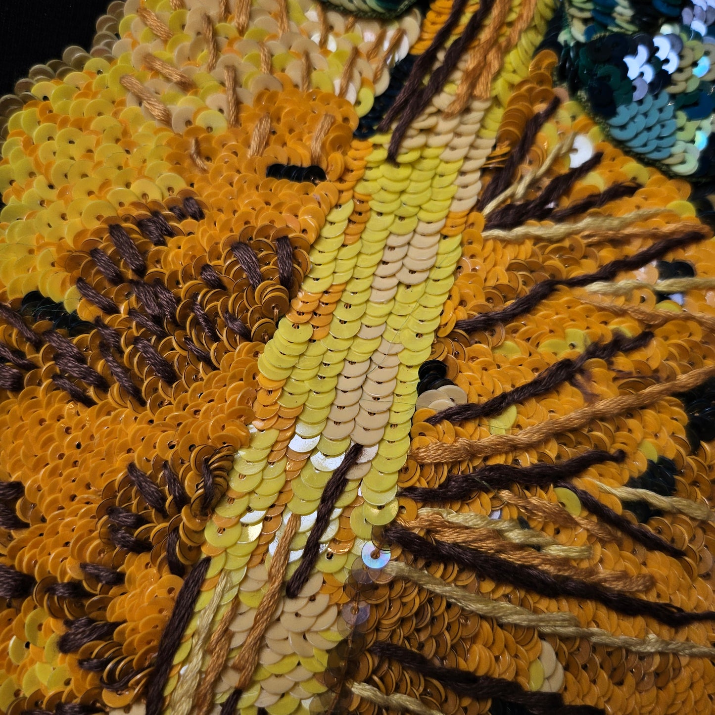 Close-up of a D&G pineapple patch, featuring shimmering yellow and orange paillettes with brown embroidery.