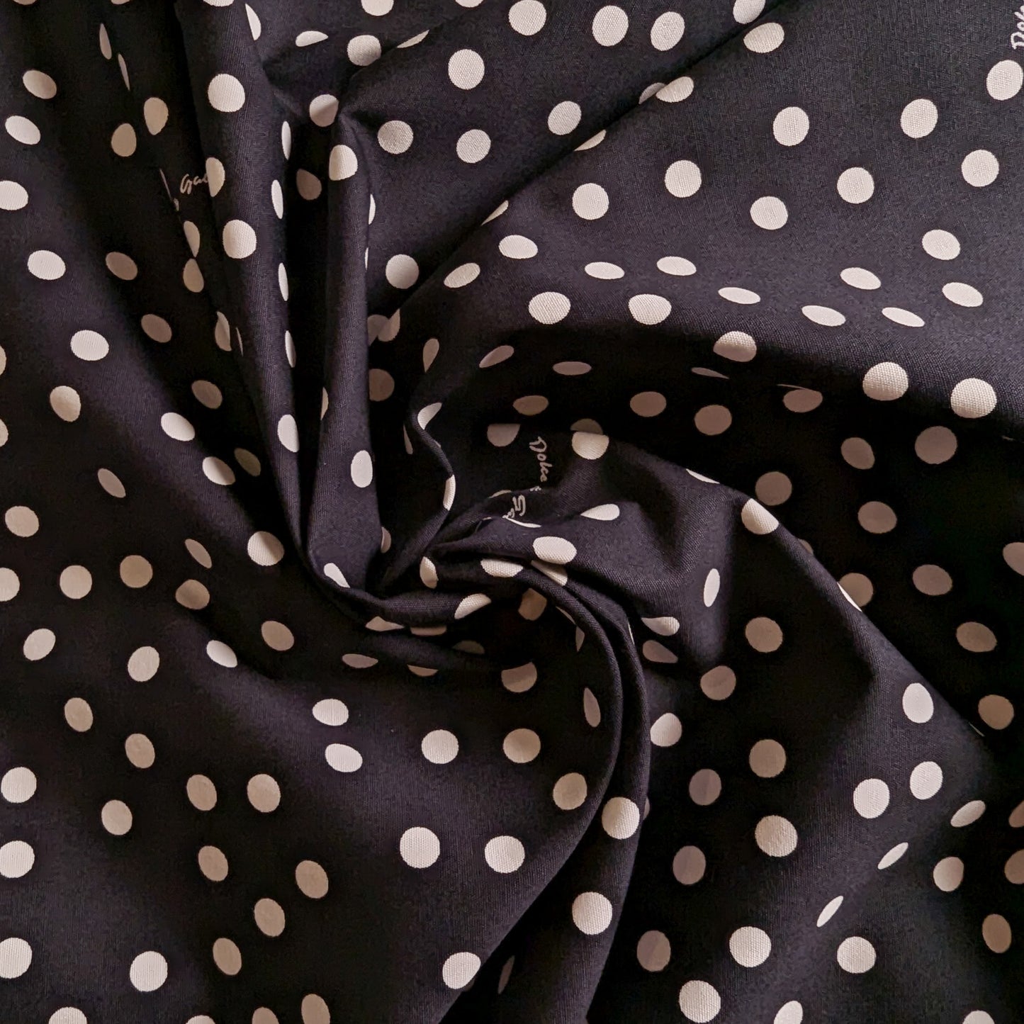Black D&G deadstock cotton fabric with white polka dots, folded to show texture.