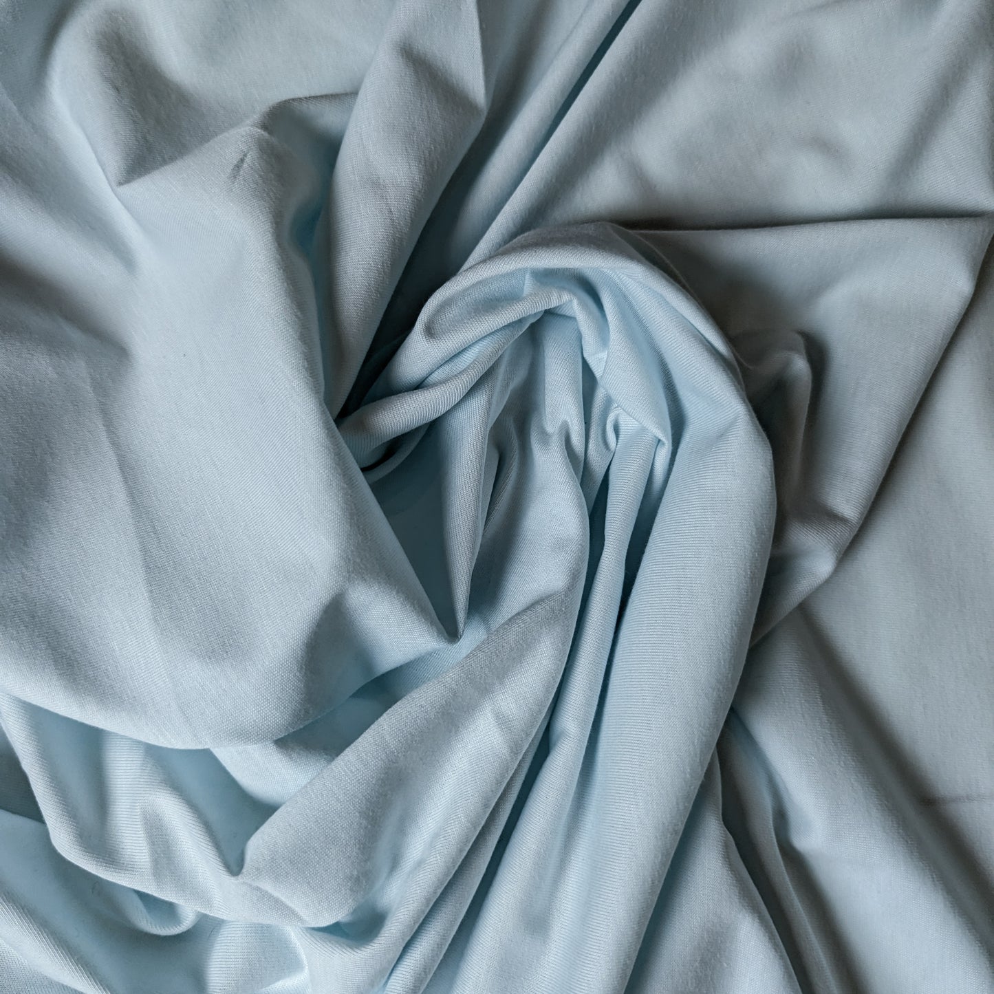 Light blue cotton jersey fabric, 165 cm wide, with soft drapes and folds.