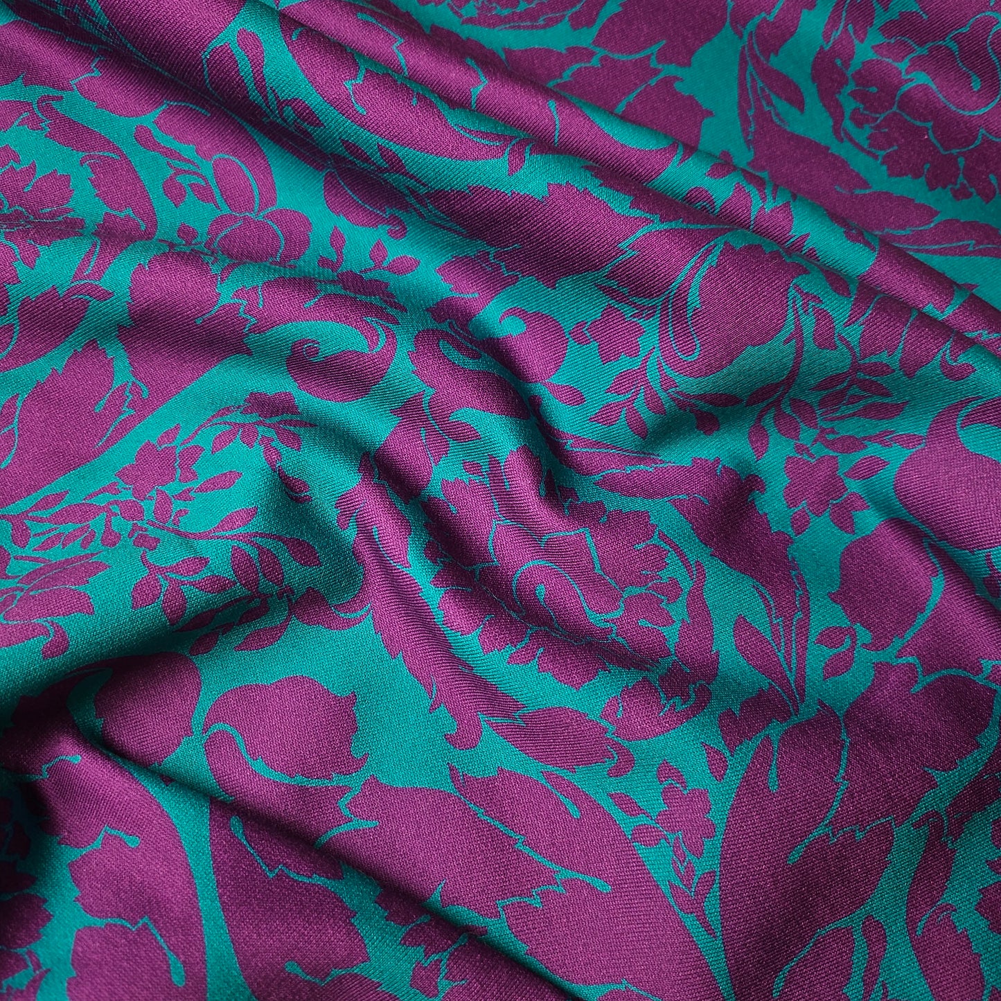 Soft V*****e Deadstock Sweat fabric in tropical green with a vibrant purple Barocco floral pattern.