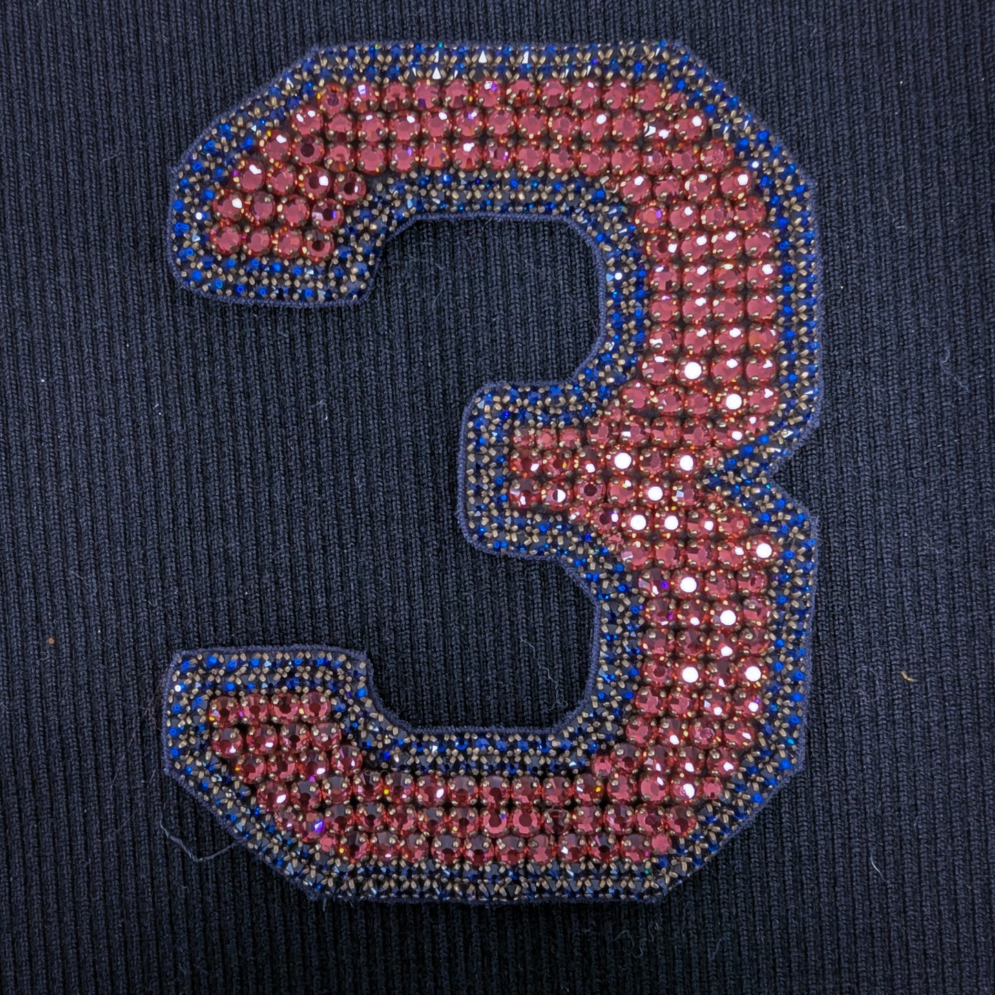 D&G number 3 patch with sparkling pink pearls and blue beaded trim on black fabric.