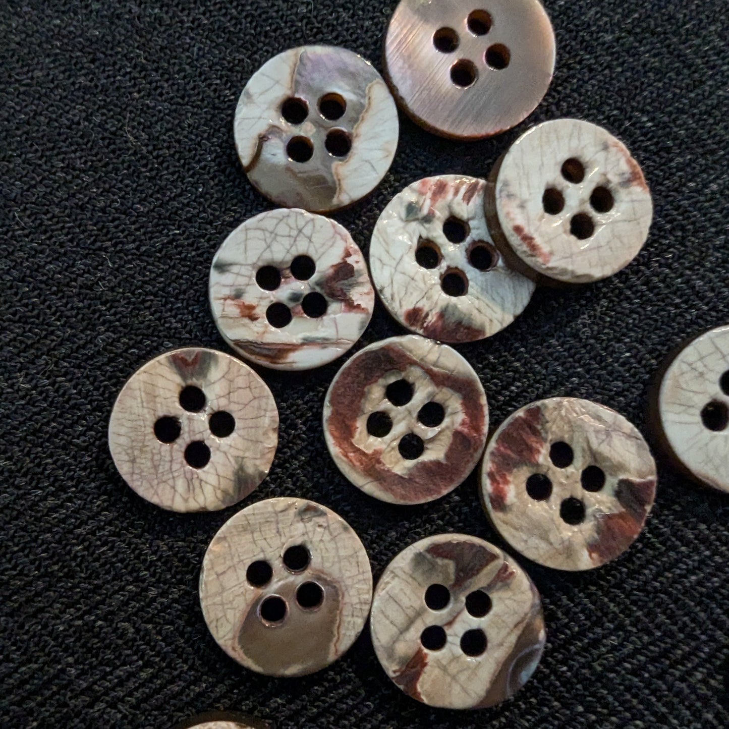 Set of 15 natural mother-of-pearl buttons, 1cm, with unique brown and white patterns and four holes.