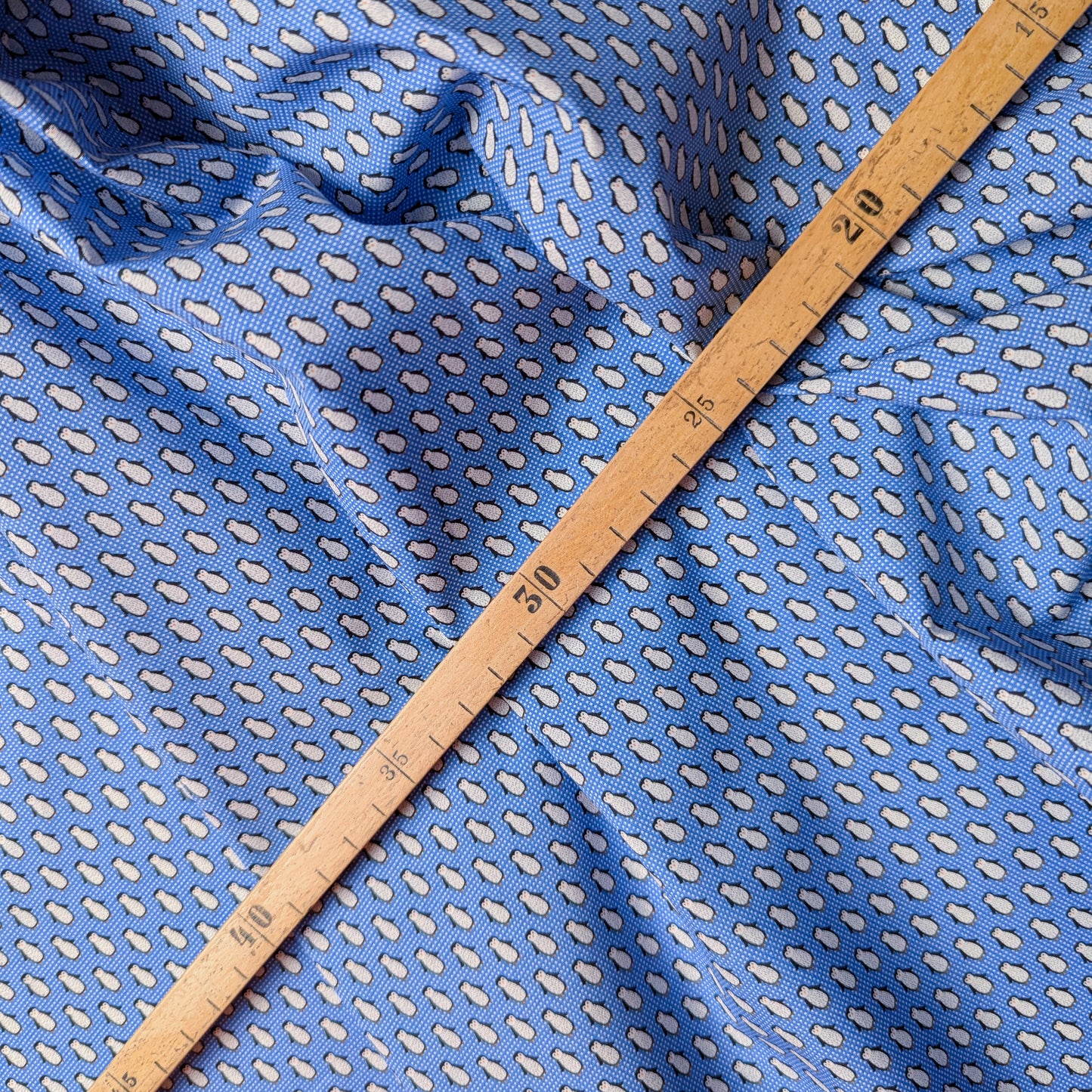 Blue cotton poplin deadstock fabric with small white droplet pattern and a wooden ruler.
