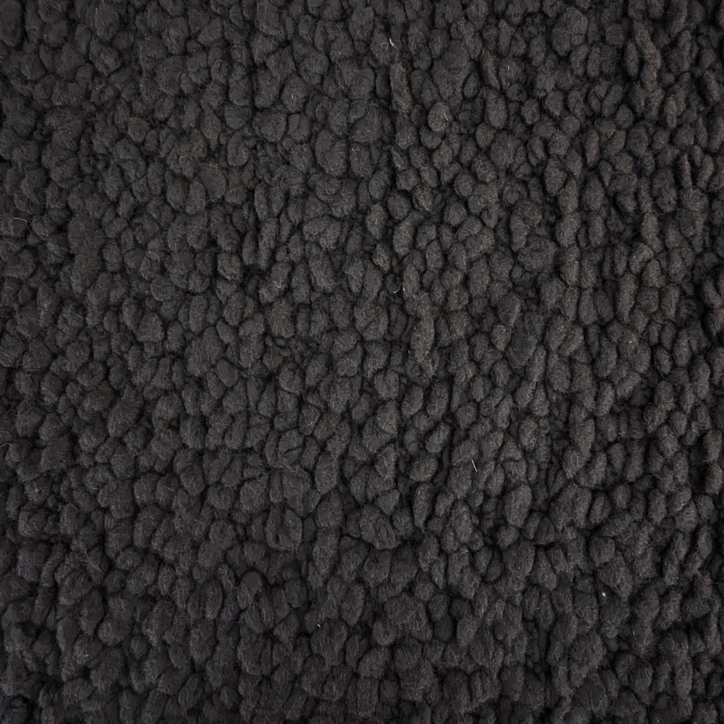 Close-up of heavy D*or deadstock wool bouclé fabric in Pantone Jet Black, showing its textured, voluminous surface.