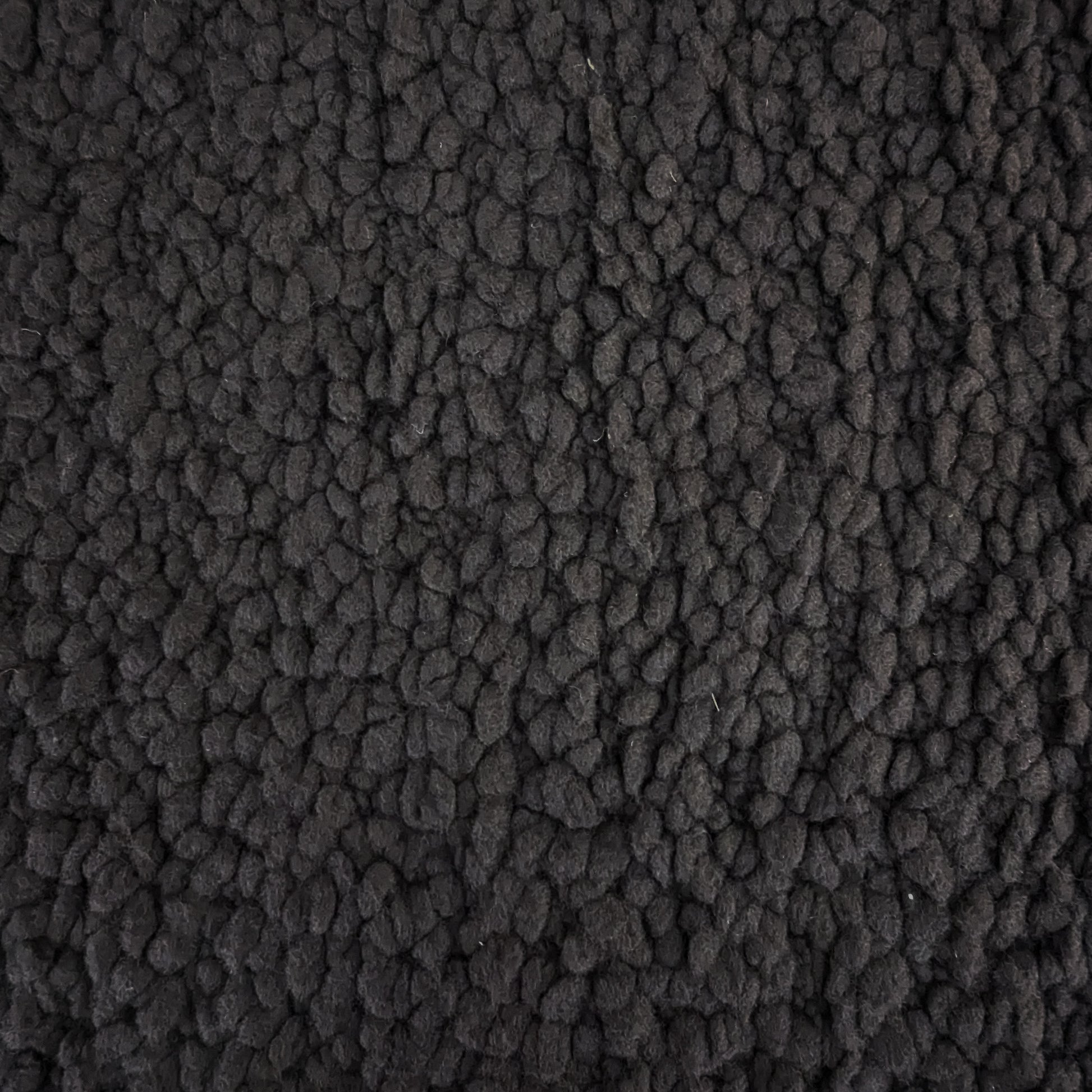 Close-up of heavy D*or deadstock wool bouclé fabric in Pantone Jet Black, showing its textured, voluminous surface.