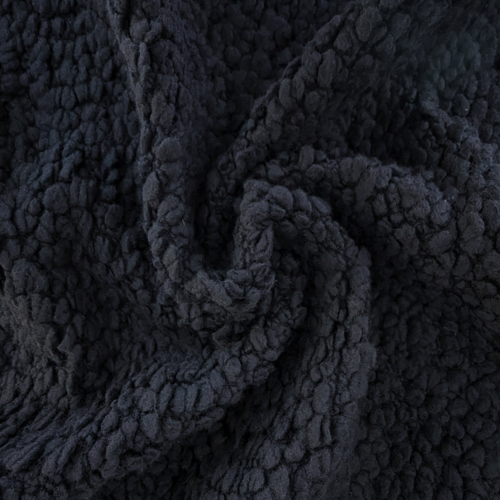 Deadstock D*or heavy black wool bouclé fabric with a textured, voluminous surface, draped in a swirl.