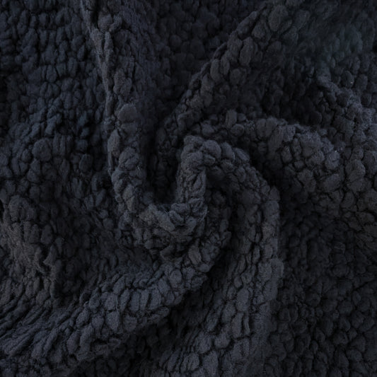 Deadstock D*or heavy black wool bouclé fabric with a textured, voluminous surface, draped in a swirl.
