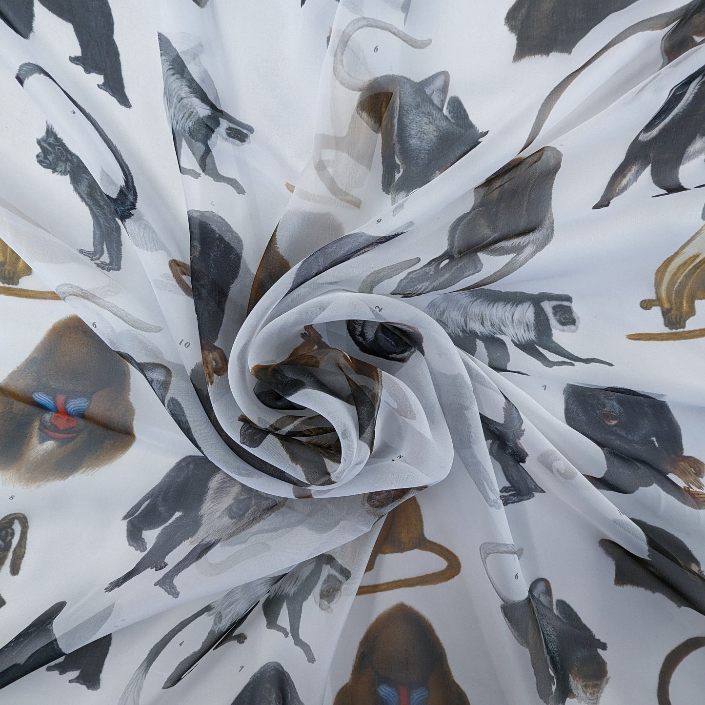 White silk chiffon fabric with a detailed, natural-colored monkey print, draped in soft folds.
