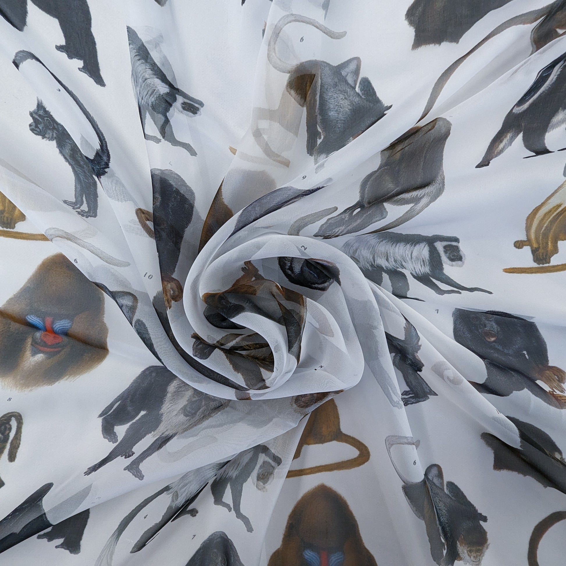 White silk chiffon fabric with a detailed, natural-colored monkey print, draped in soft folds.