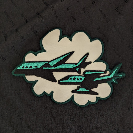 Designer deadstock patch: black and teal planes flying through a white cloud, 20x14cm.