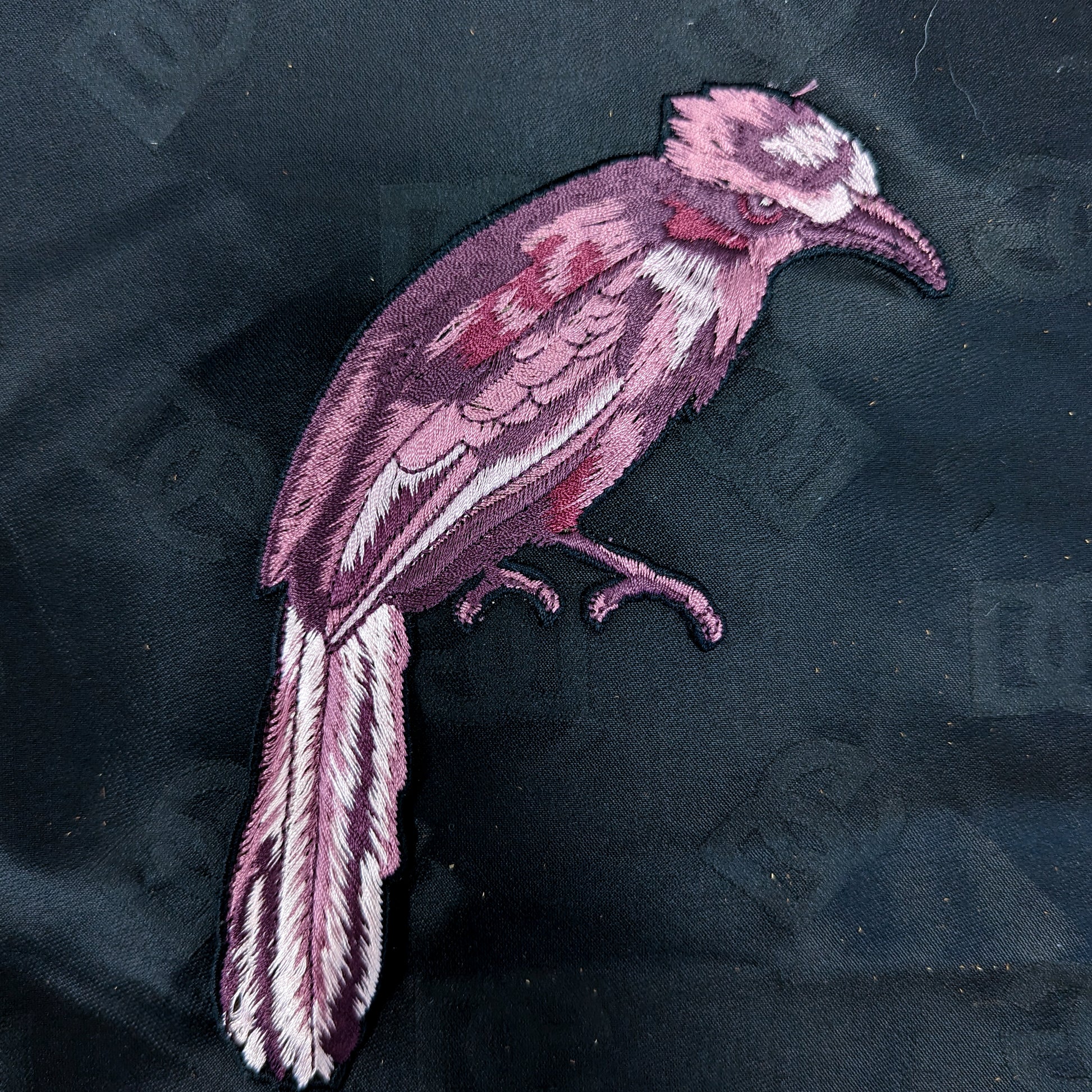 Lila embroidered bird patch, 10x19cm, with detailed feathers and beak on dark fabric.