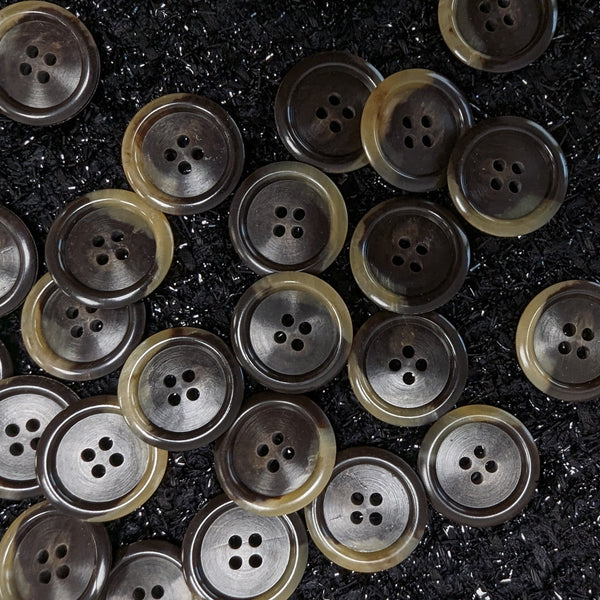 Round, 2.5cm, dark brown and beige marbled buttons with four holes, scattered on a black textured surface.