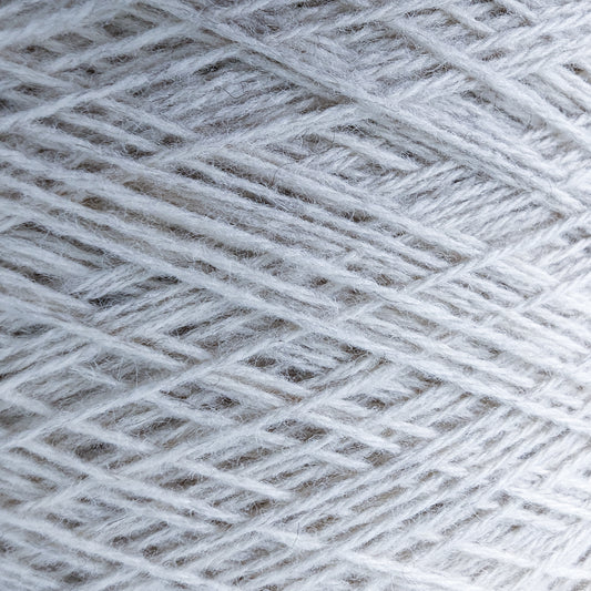 Close-up of natural white 50% yak, 50% merino yarn on a cone, showing its soft texture.