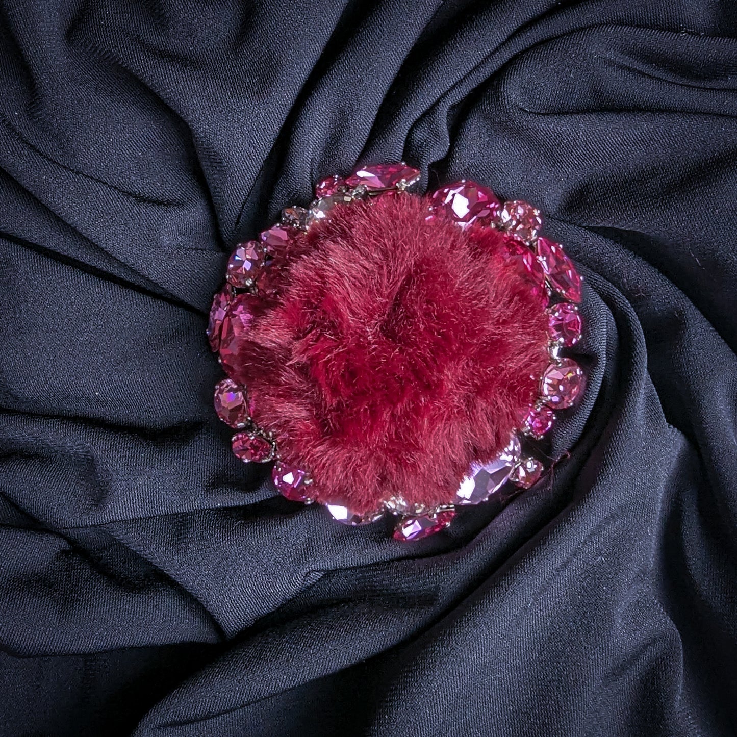 Burgundy fur ornament with pink and rose Swarovski crystals, 7x7cm, on dark fabric.