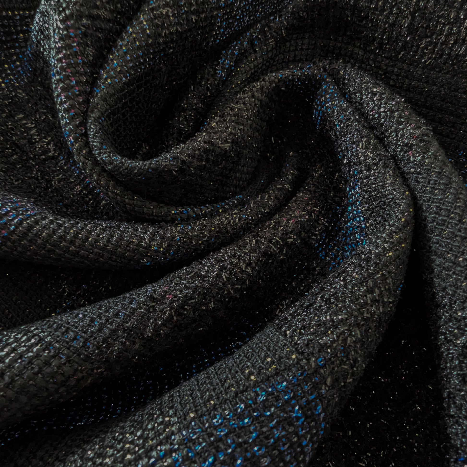 Dark gray doubleface tweed fabric with subtle colorful flecks, folded in a spiral.