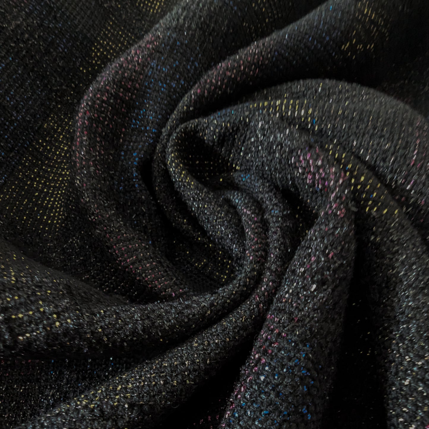 Dark gray doubleface tweed fabric with colorful flecks, draped in soft folds.