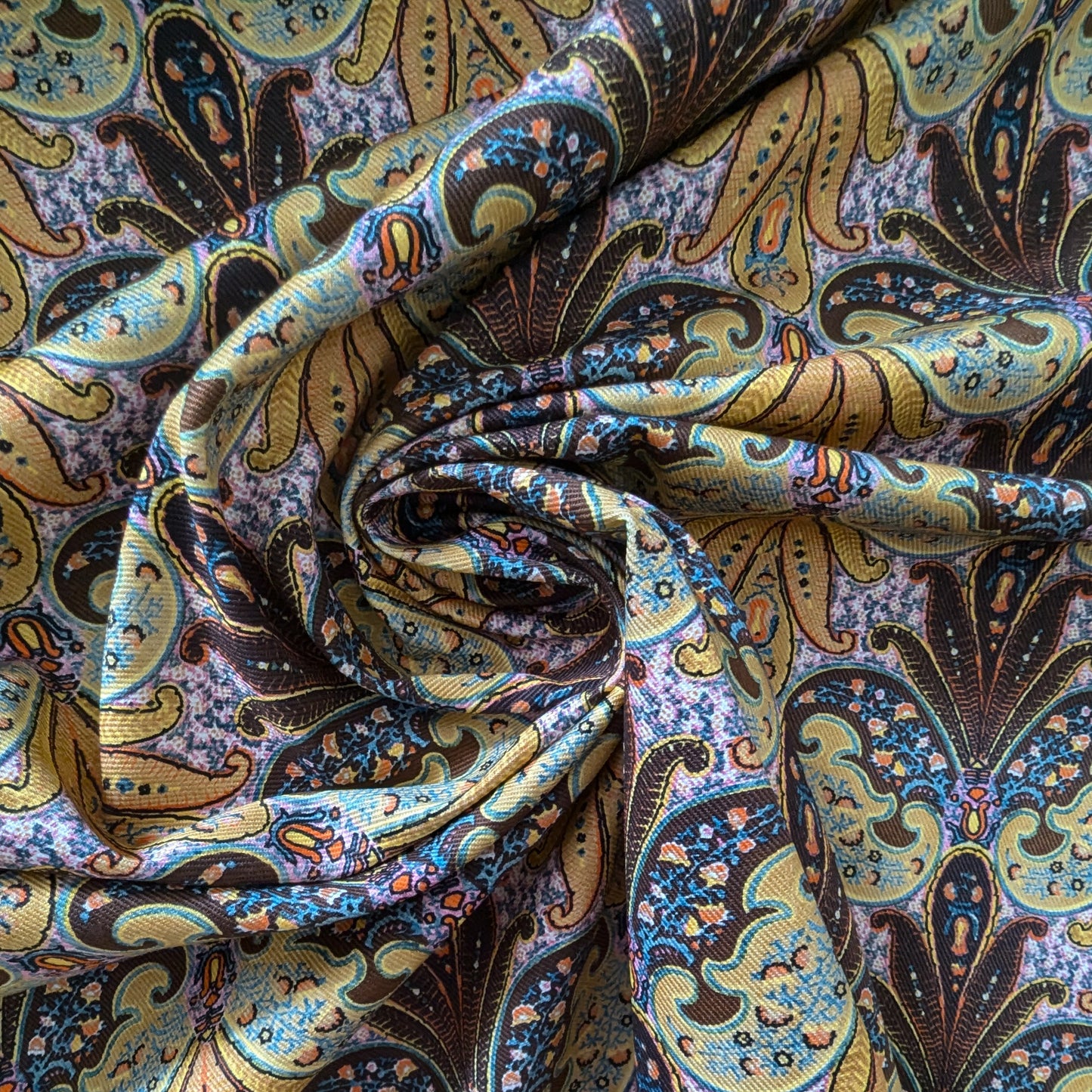 Deadstock E##o denim fabric with a vibrant paisley print in gold, blue, and brown.