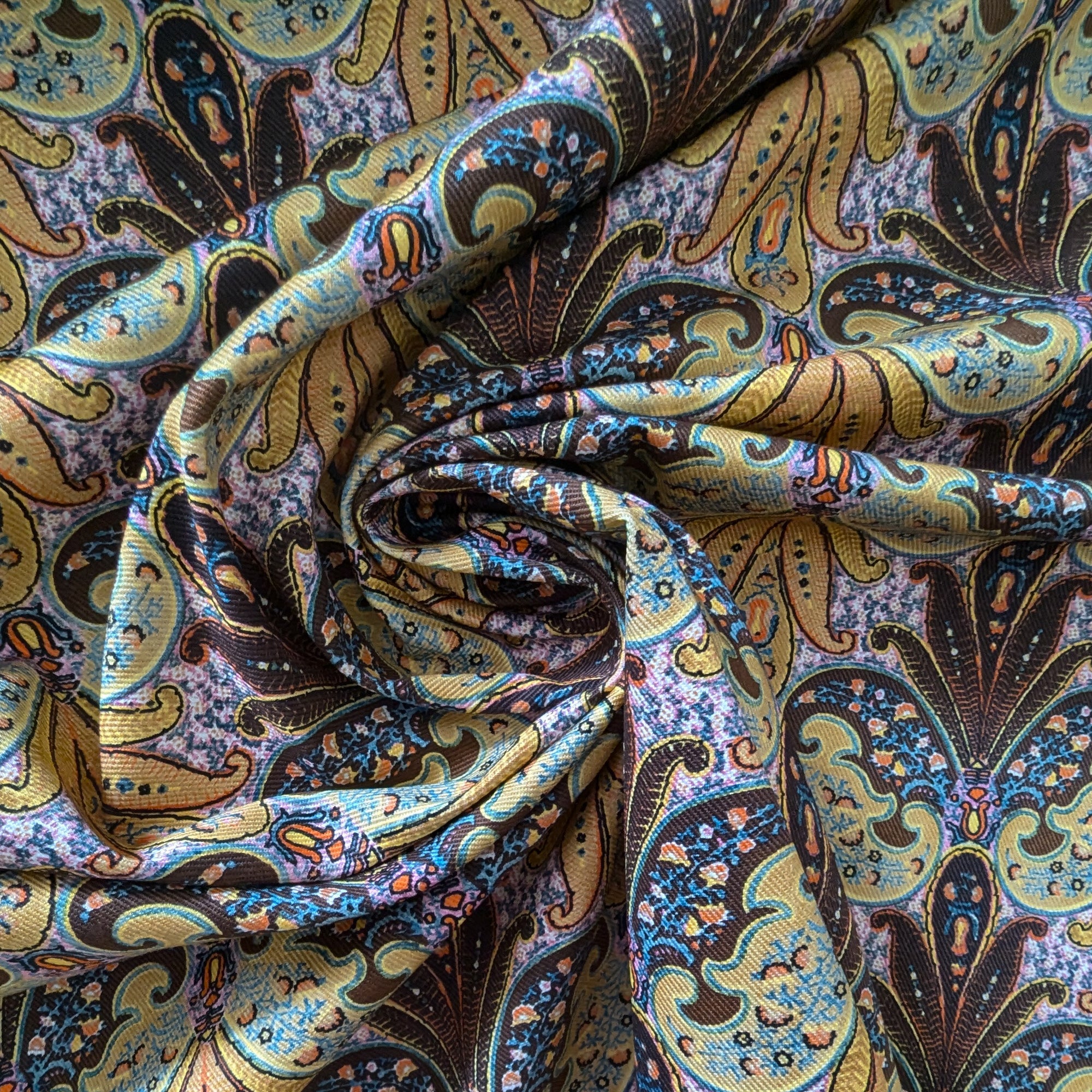 Etr* deadstock denim fabric with a colorful gold, blue, and brown paisley print, artfully swirled.