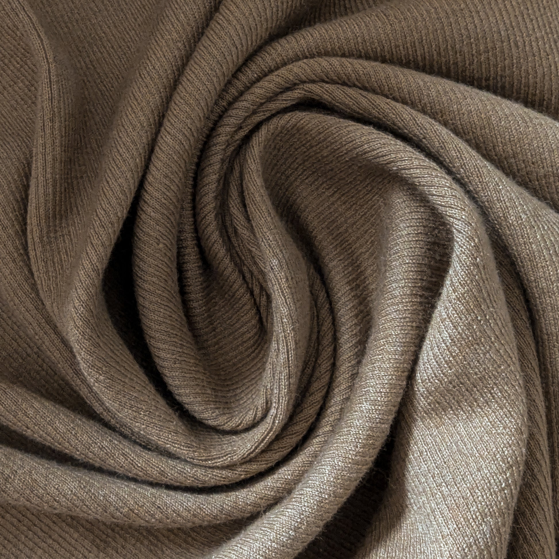 Camel cotton-cashmere rib jersey fabric, soft and uni, folded in a spiral.