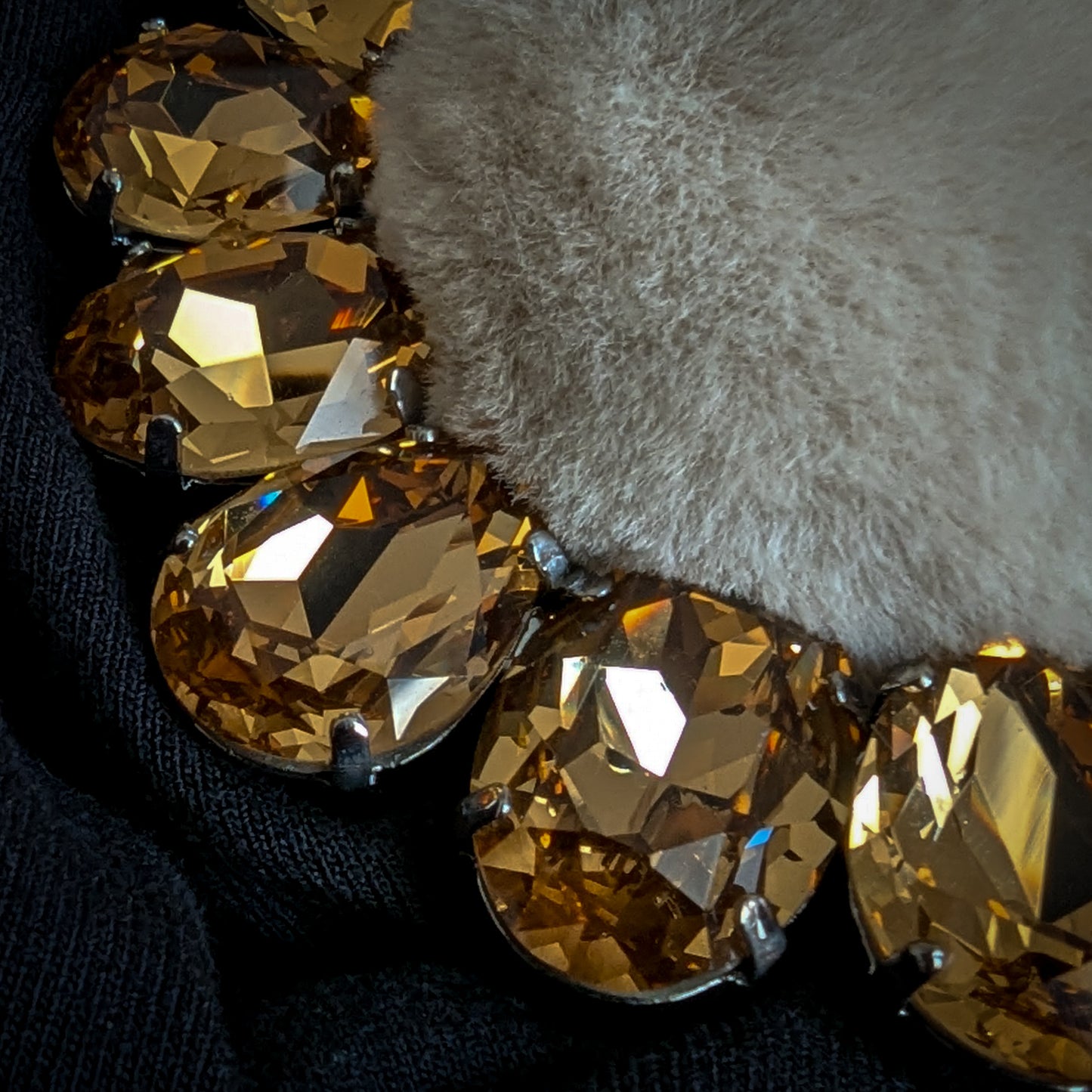 D&G Zierornament with golden Swarovski stones and light brown faux fur on black fabric.