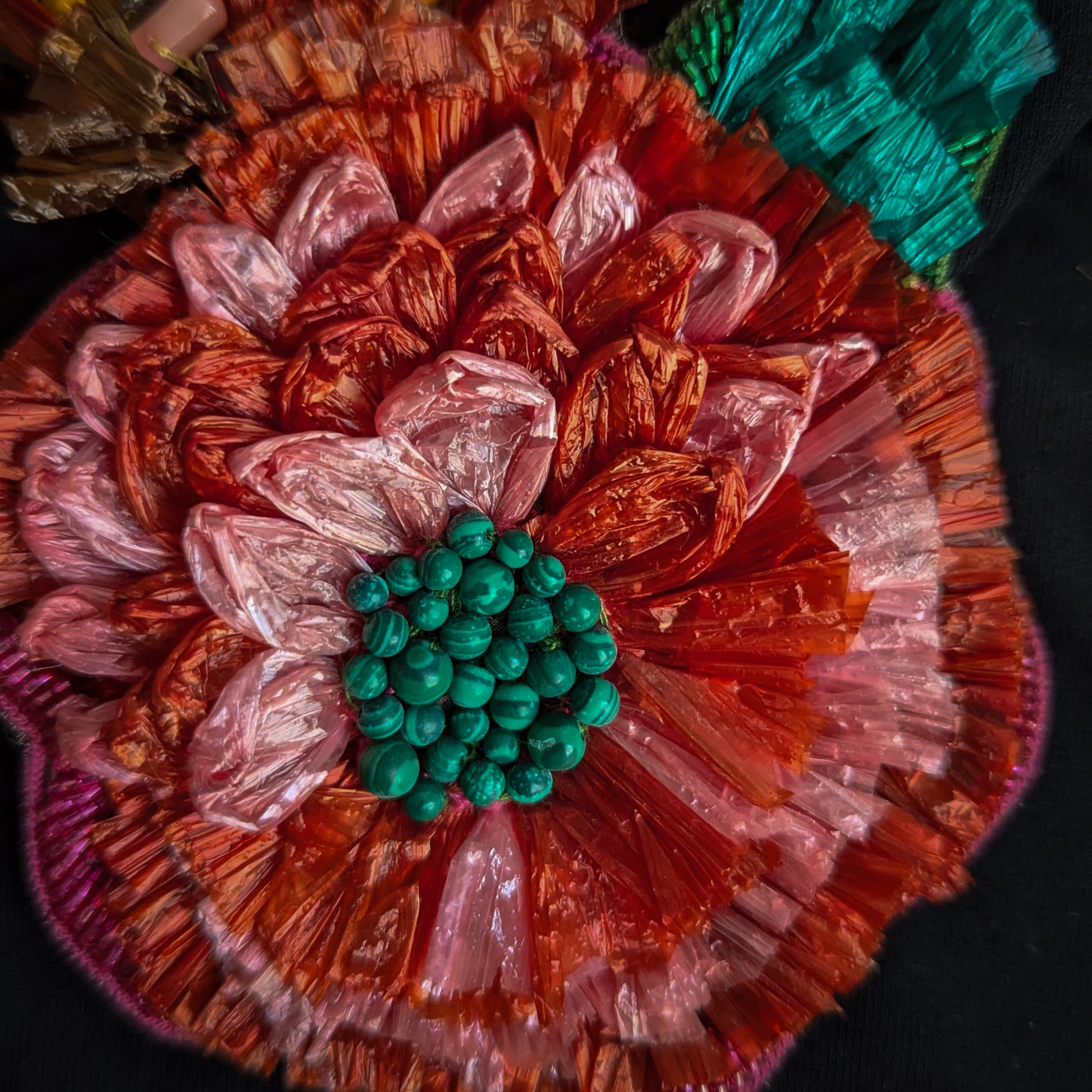 3D D&G raffia flower embellishment with pink and orange petals and a green beaded center.