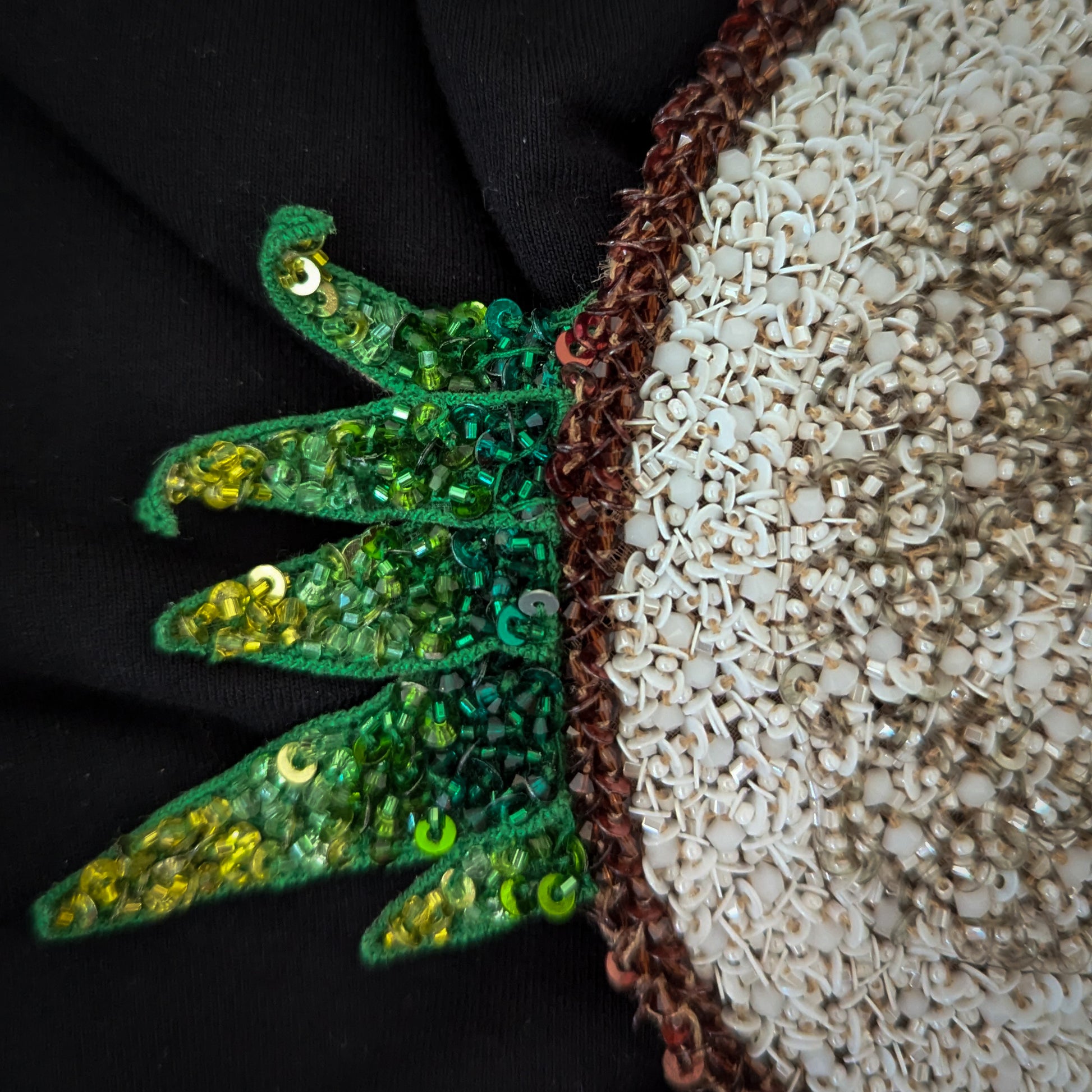 D&G coconut leaf patch with green sequins, beads, and white pearls on a black background.