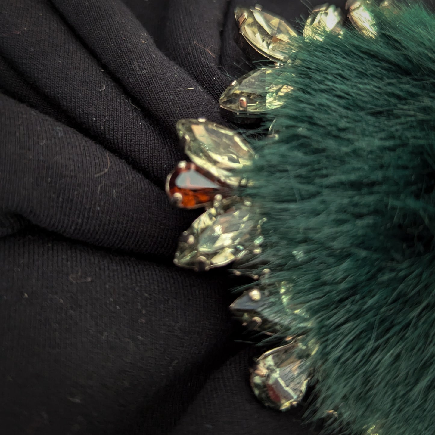 Green fur ornament with Swarovski stones, 9x9 cm, on black fabric.