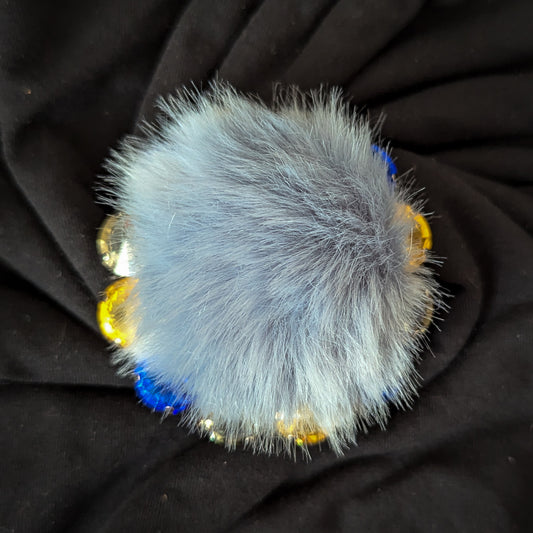 Blue-gray faux fur ornament with gold and blue Swarovski crystals, 7cm x 7cm.