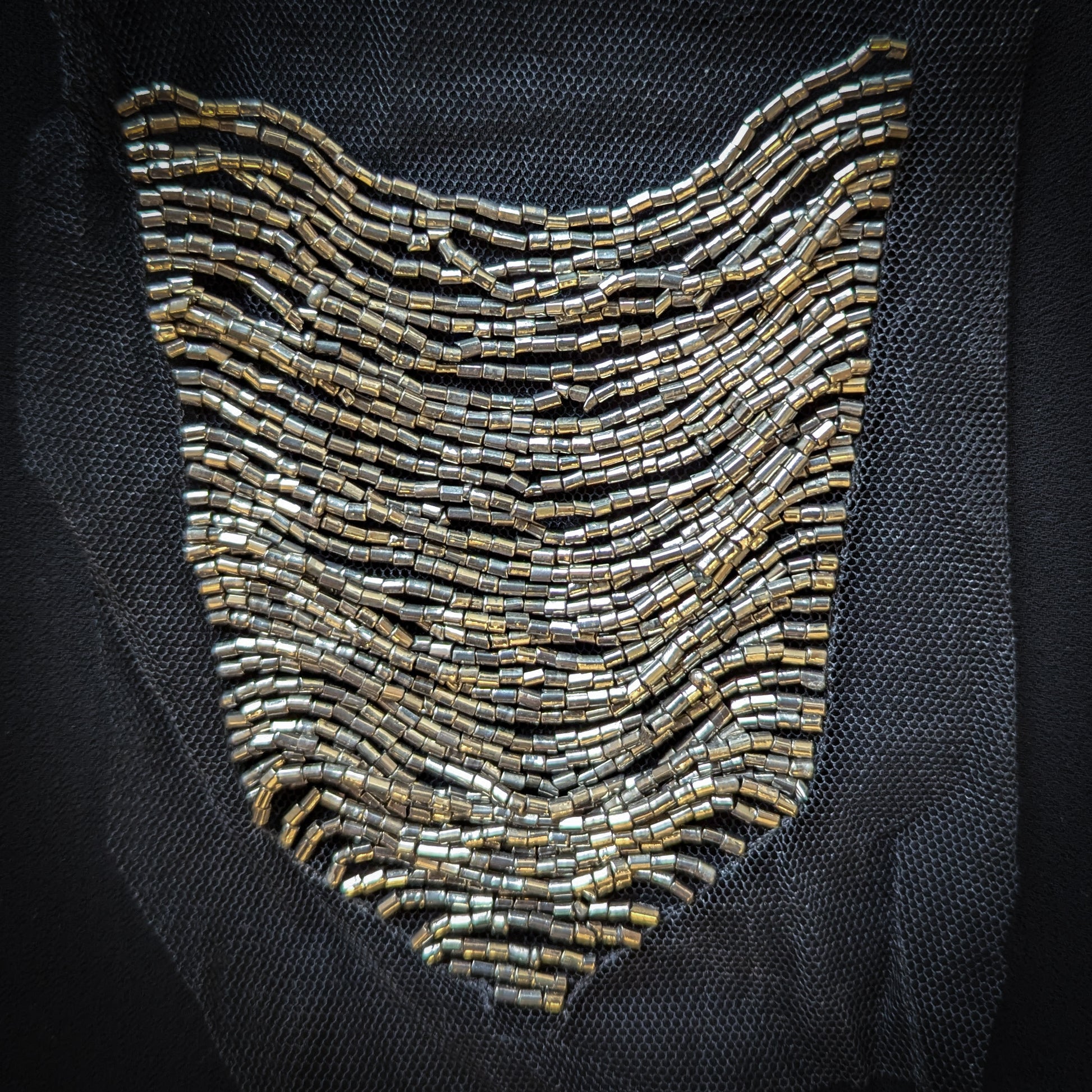 Silver beaded crest-shaped tulle patch, 12x15cm, on black mesh.
