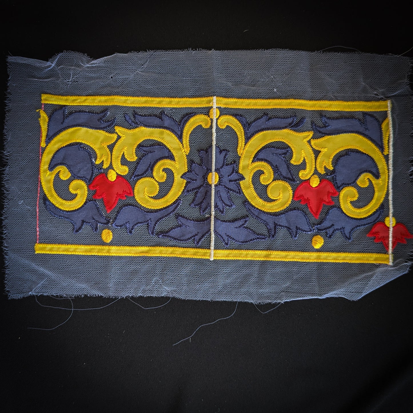 Embroidered D&G tulle trim, 13x30cm, featuring yellow scrollwork and red leaves on a dark blue background.