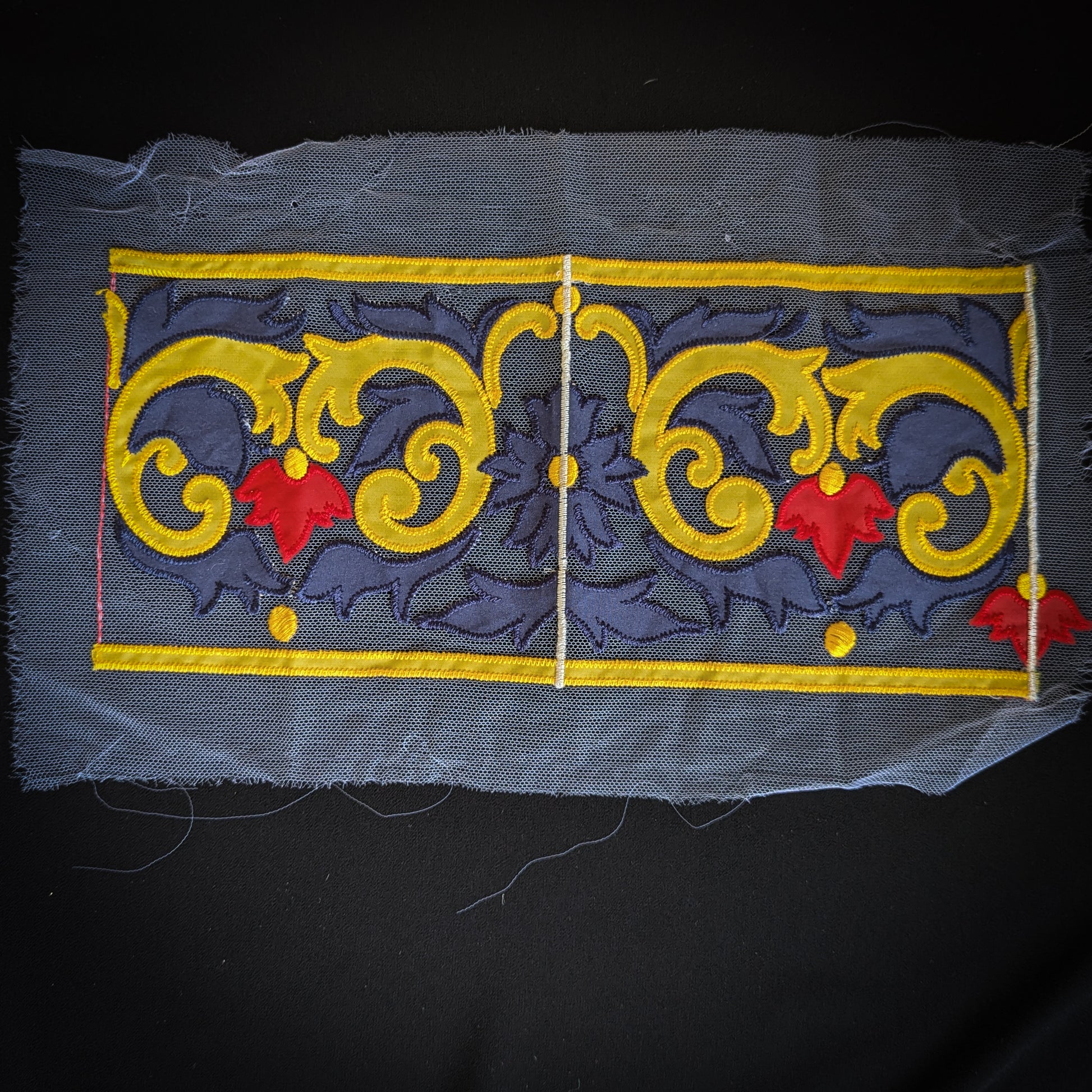 Embroidered D&G tulle trim, 13x30cm, featuring yellow scrollwork and red leaves on a dark blue background.