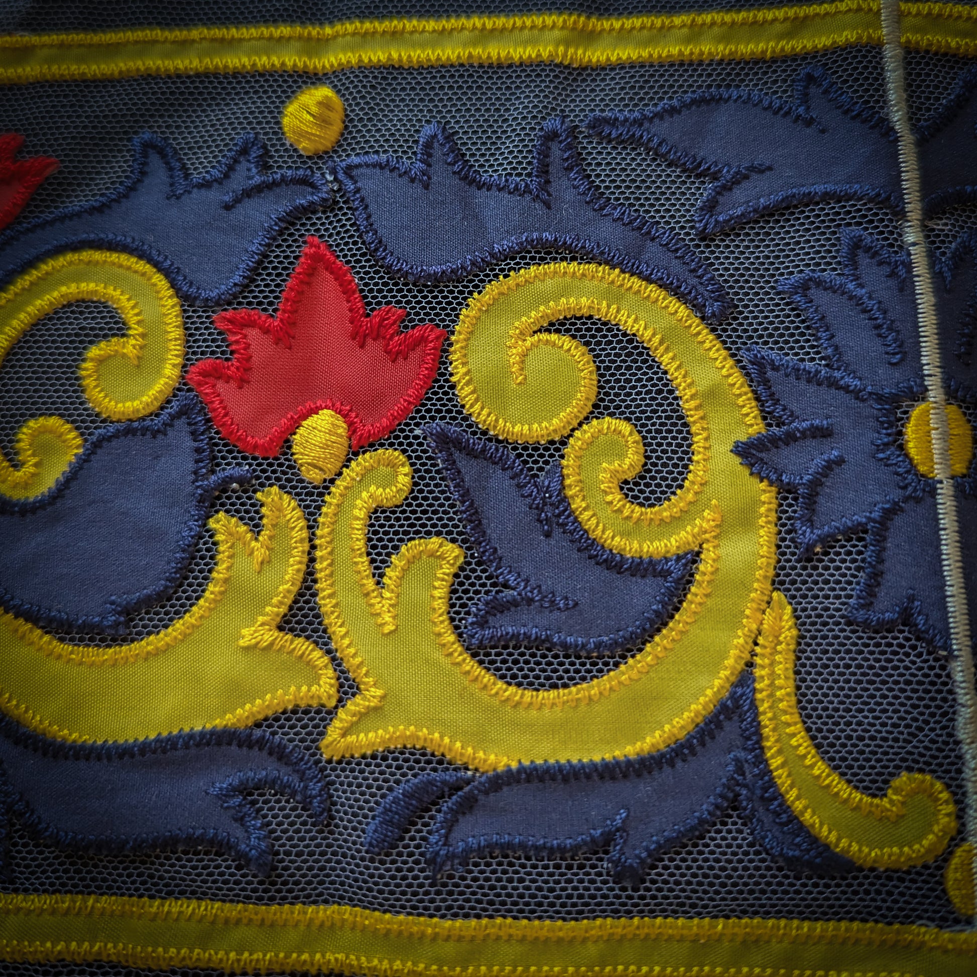 Embroidered D&G tulle trim, 13x30cm, with yellow scrollwork and a red floral design on dark blue.