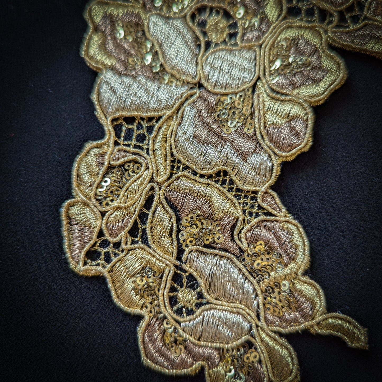 Golden lace trim with sequins, 10x15cm, featuring intricate floral embroidery on dark fabric.